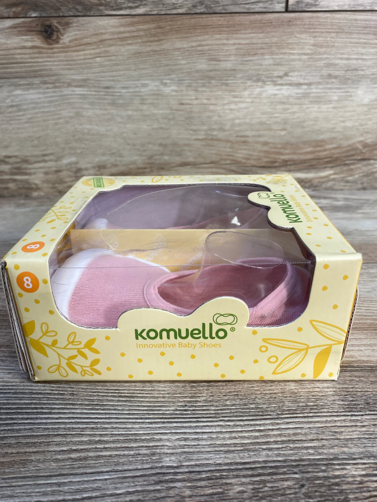 Komuello innovative baby shoes in pink, size 8, in yellow box on wooden surface