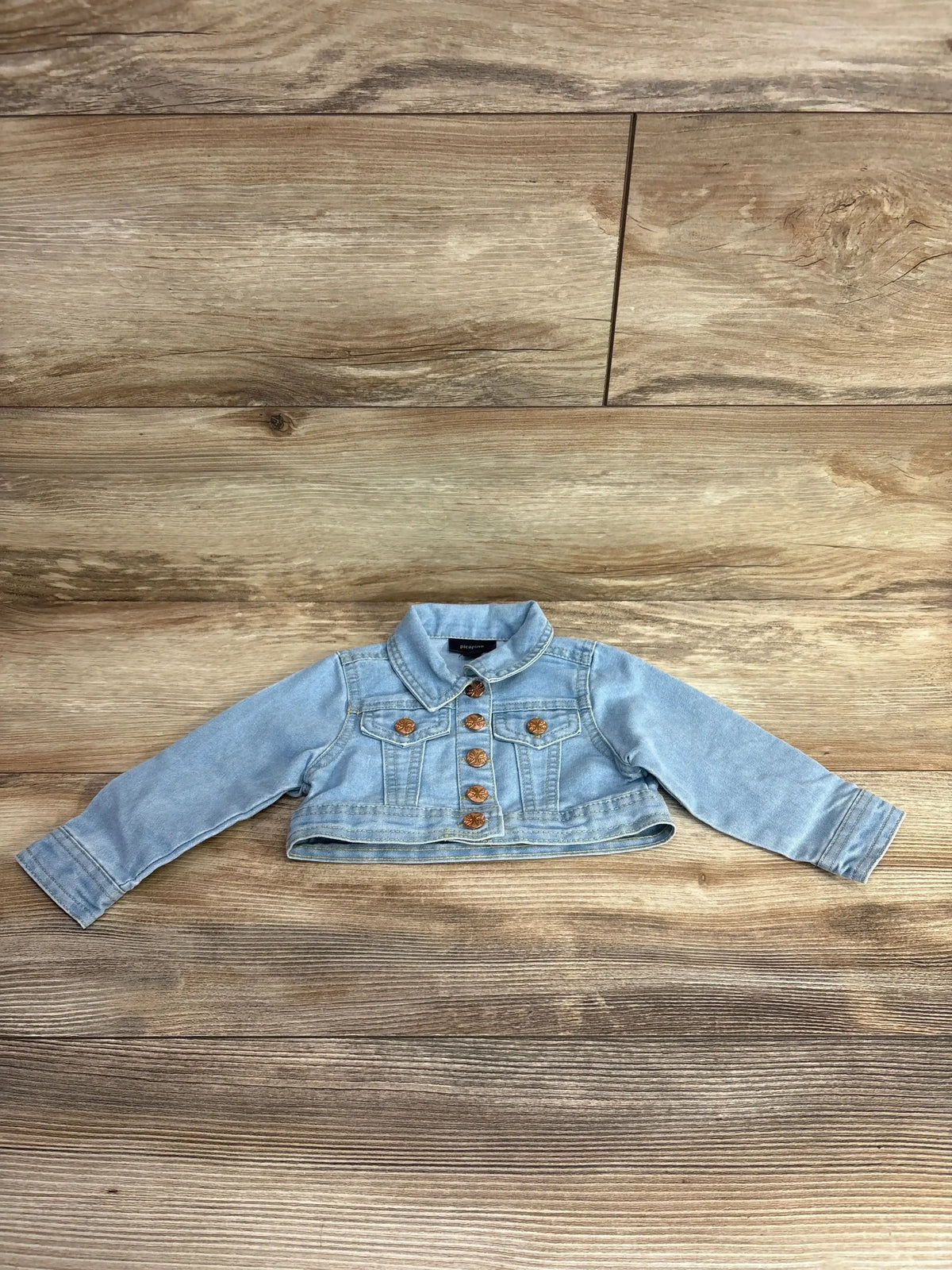 Light blue cropped denim jacket with gold buttons for toddlers displayed on wooden floor