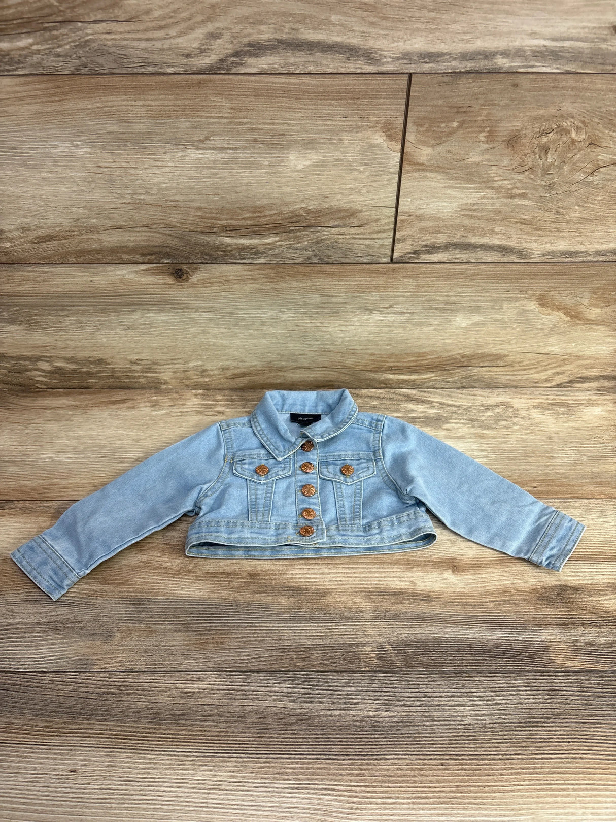 Light blue cropped denim jacket with gold buttons for toddlers displayed on wooden floor