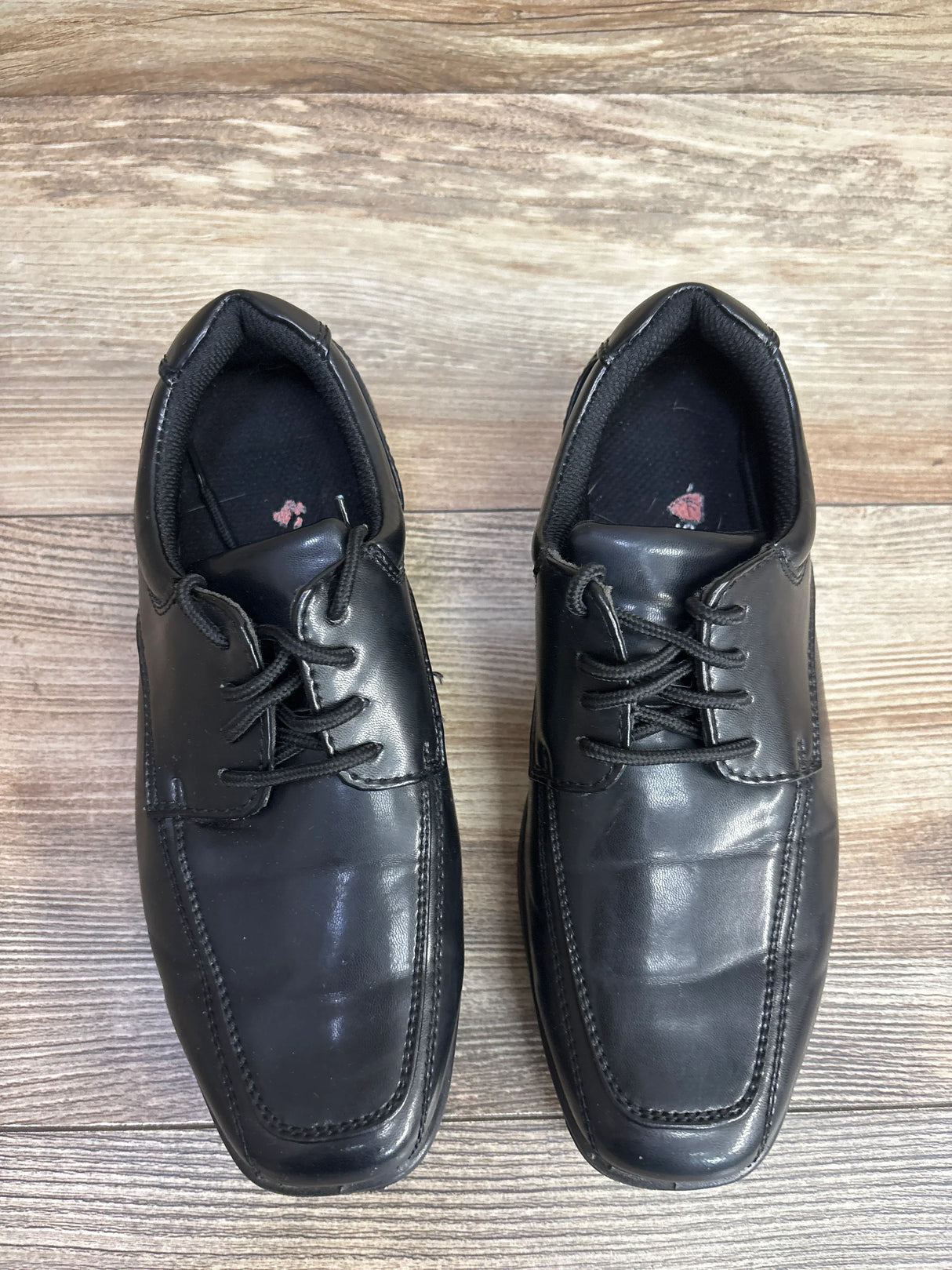 Overhead view of Deer Stags Sharp black leather lace-up dress shoes, size 2Y, showing square toe on wooden floor