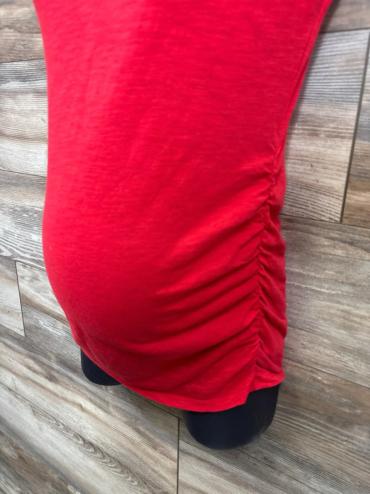 Close-up of Motherhood Maternity ruched shirt showcasing red textured fabric with side ruching detail on dress form