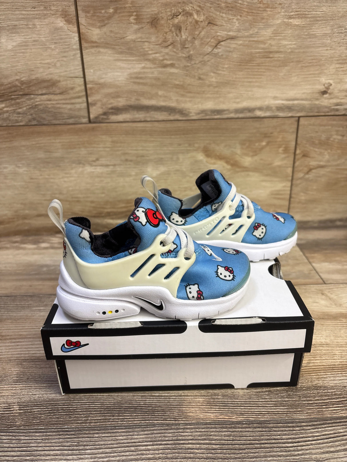 Side view of Hello Kitty Nike Air Presto TD toddler sneakers in University Blue with Hello Kitty print and white midsole on box