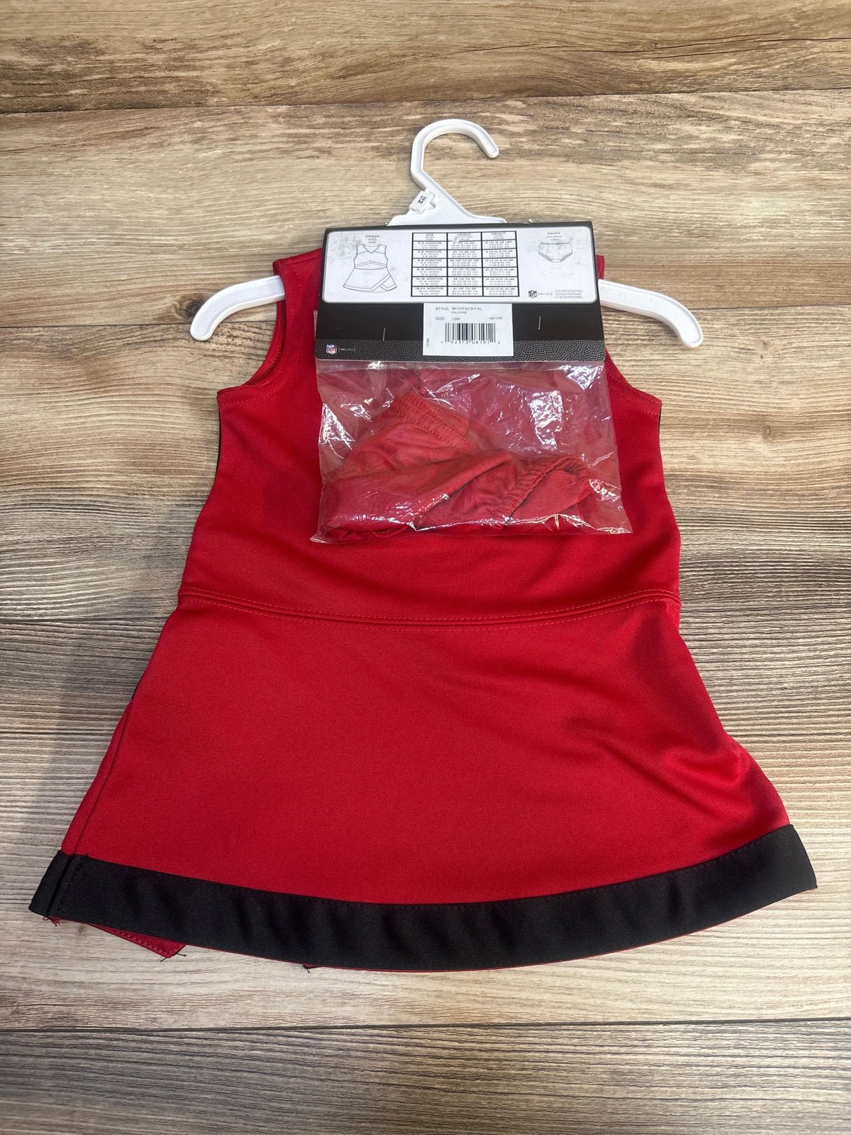 Red and black sleeveless toddler dress with matching underwear on white hanger on wood surface