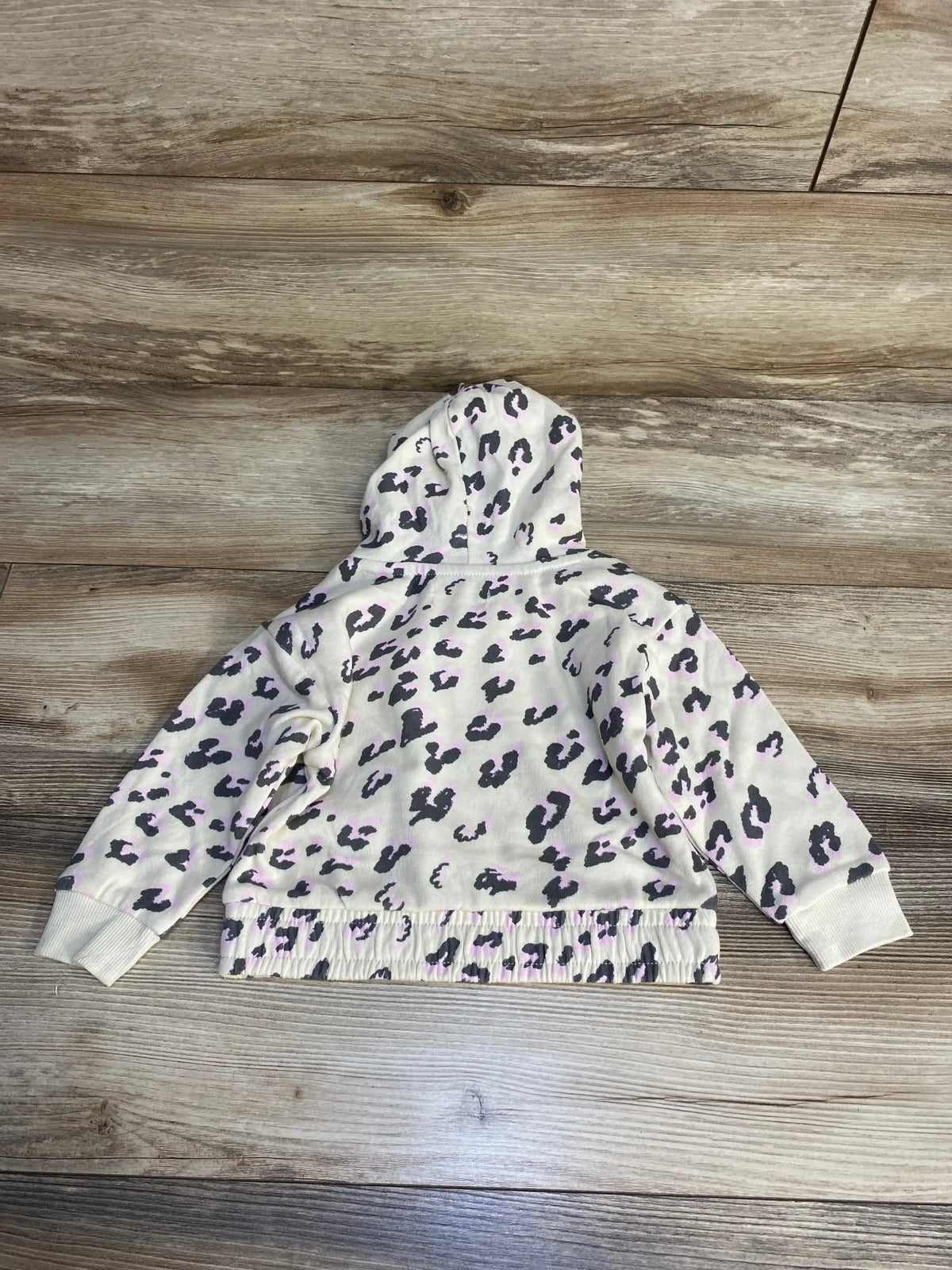 Children's hoodie with pink and black leopard print on cream background, laid flat.
