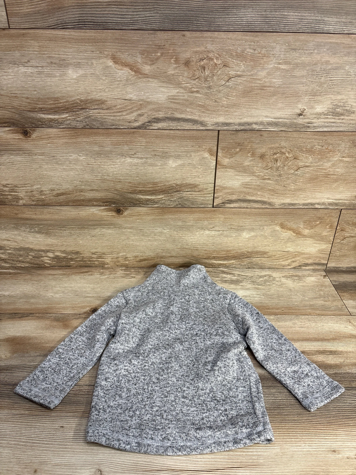 Gray knit toddler sweater with long sleeves on wooden floor background
