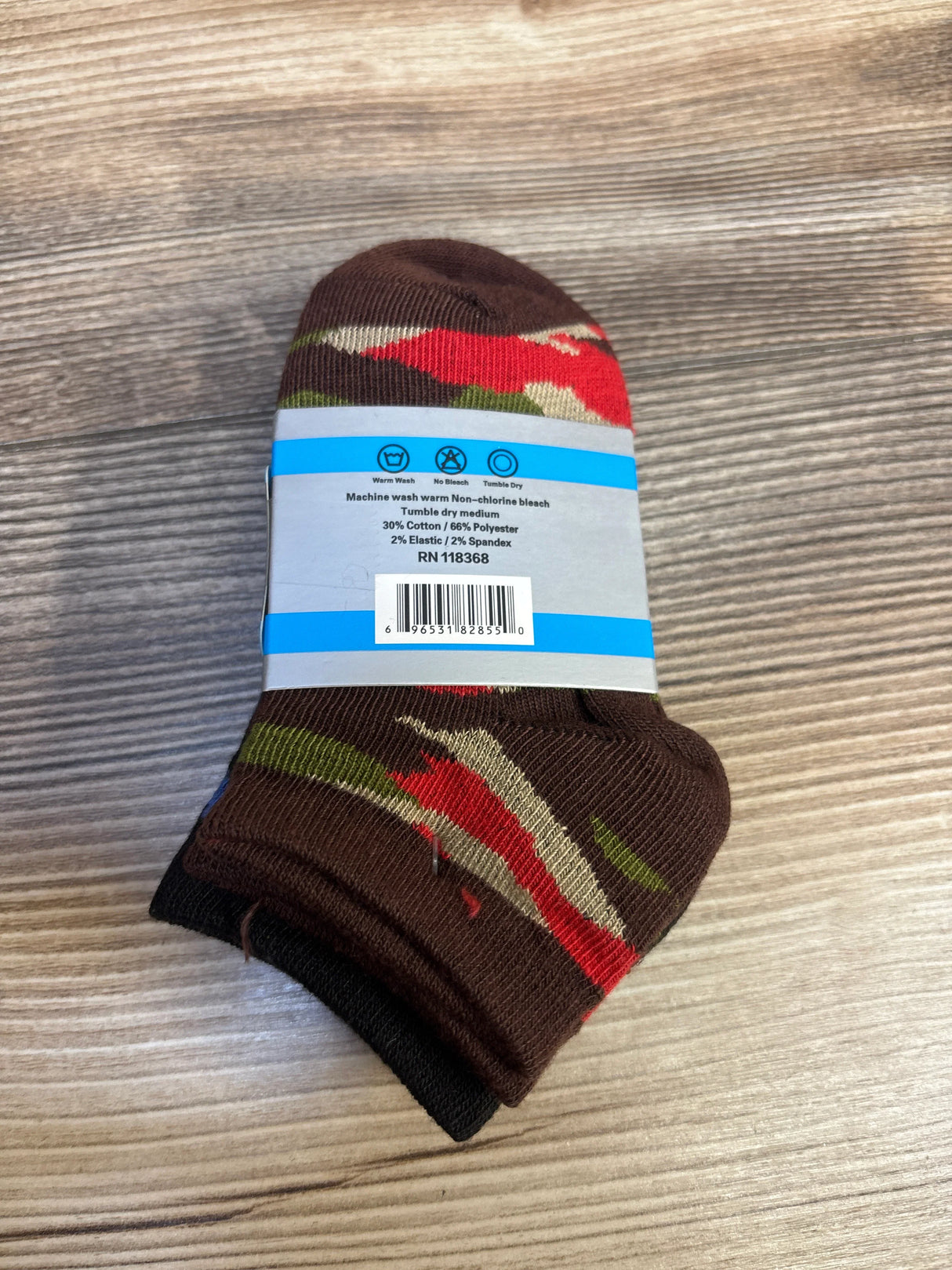 Pair of brown kids socks with camouflage green and red pattern on wood surface