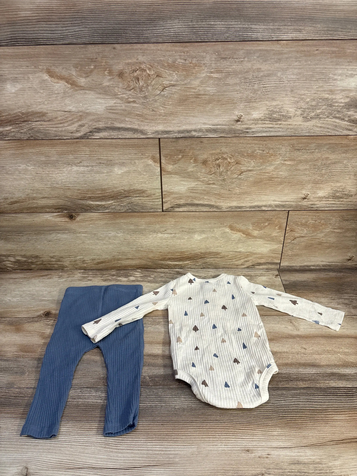 Front view of Easy Peasy 2-piece beige henley bodysuit and pants set showcasing ribbed, patterned fabric on wood background