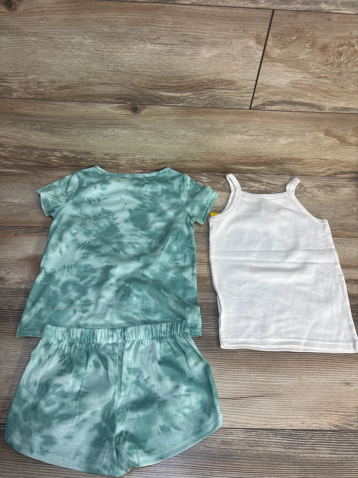 Kids' green tie-dye T-shirt and shorts set with white tank top on wood floor
