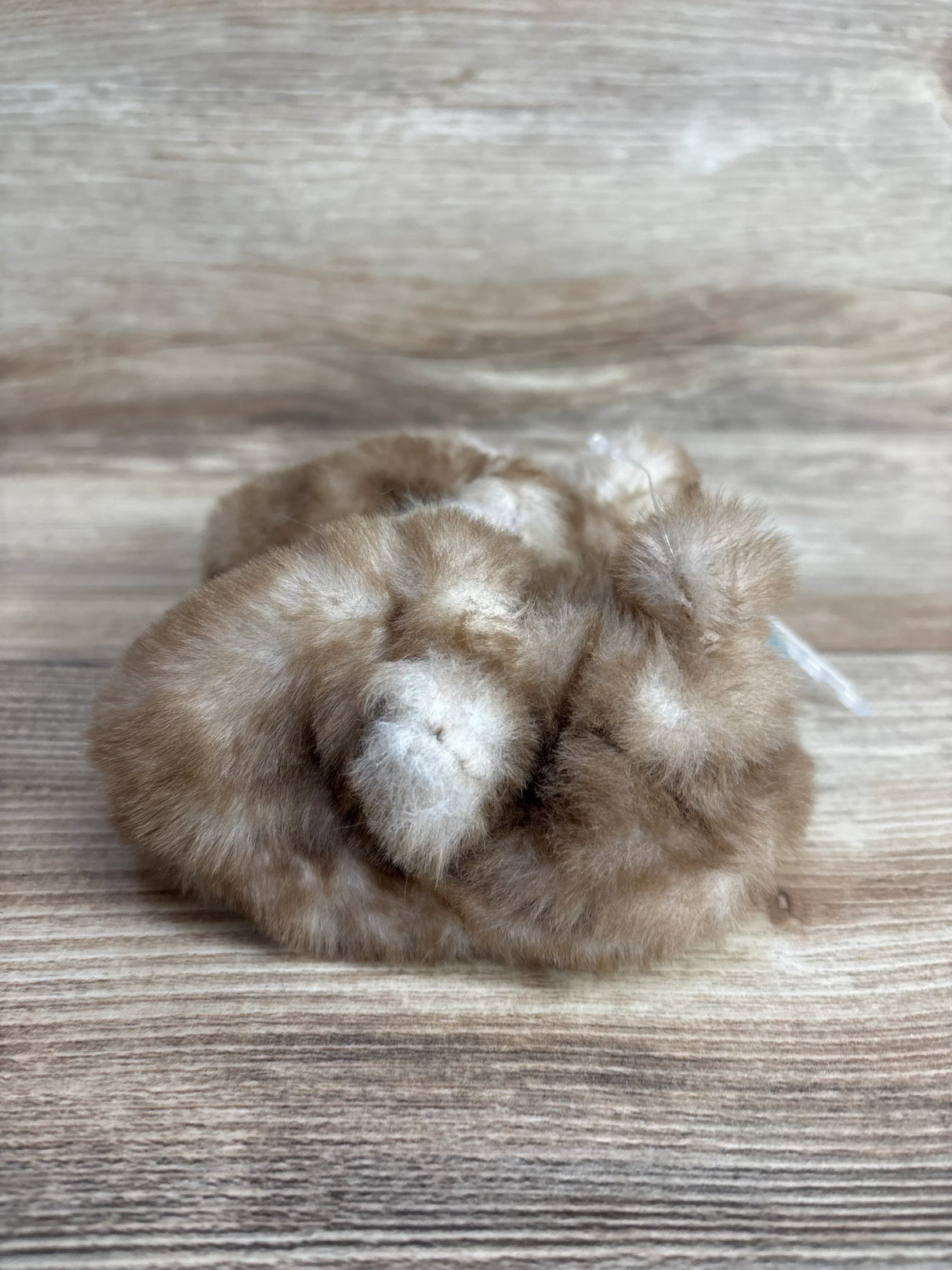 Soft brown and white faux fur baby booties on wooden surface, cozy kids clothing accessory