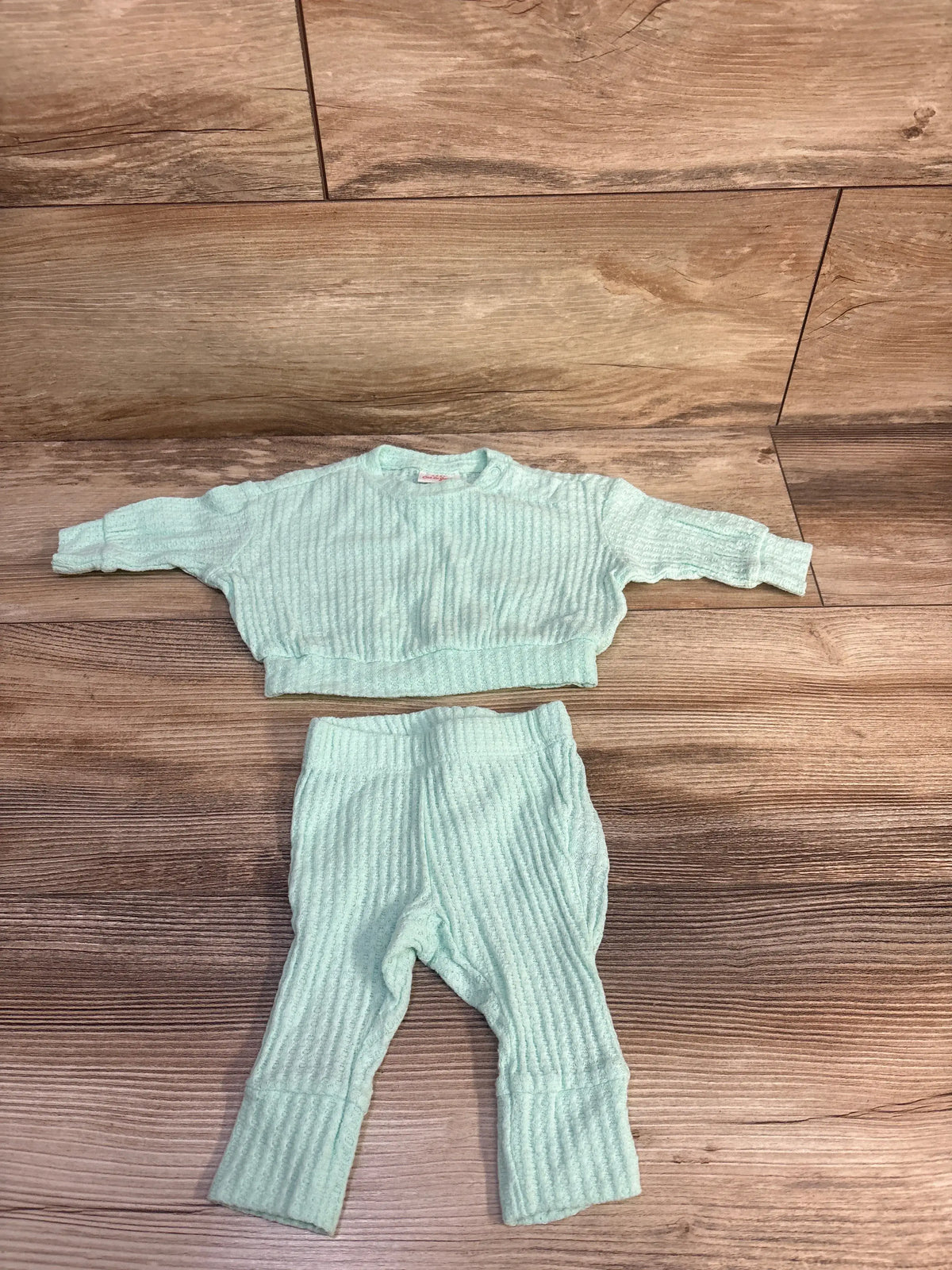 Flat lay of Cat and Jack textured shirt and pants set in teal on a wood floor