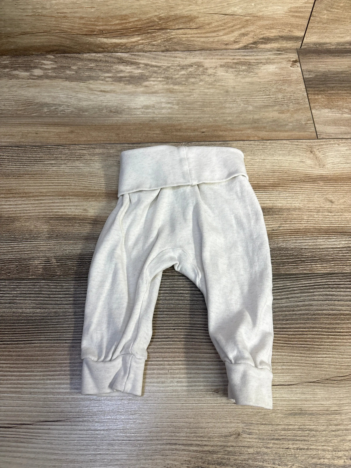 Front view of white H&M baby pants in size 3 months showcasing foldover waistband and ribbed cuffs on wood floor