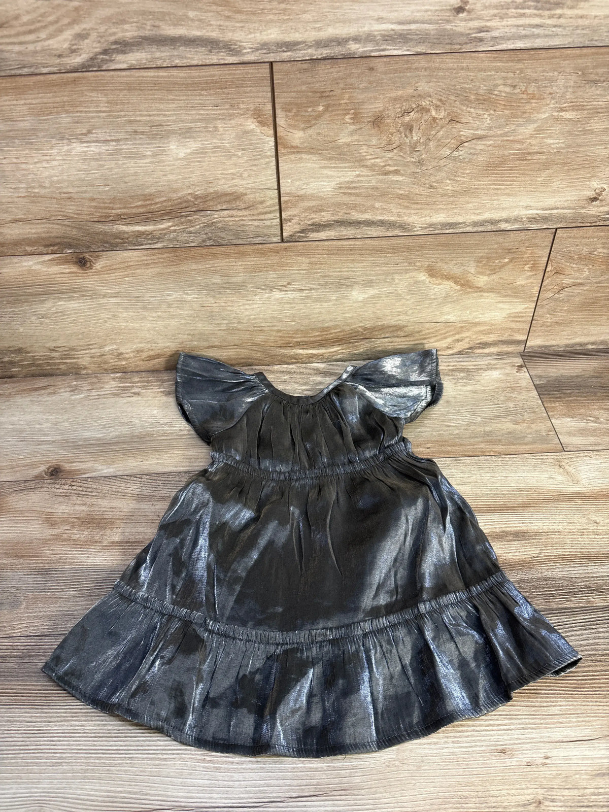 Front view of Wonder Nation metallic dress in silver showcasing flutter sleeves and tiered skirt on a wood floor