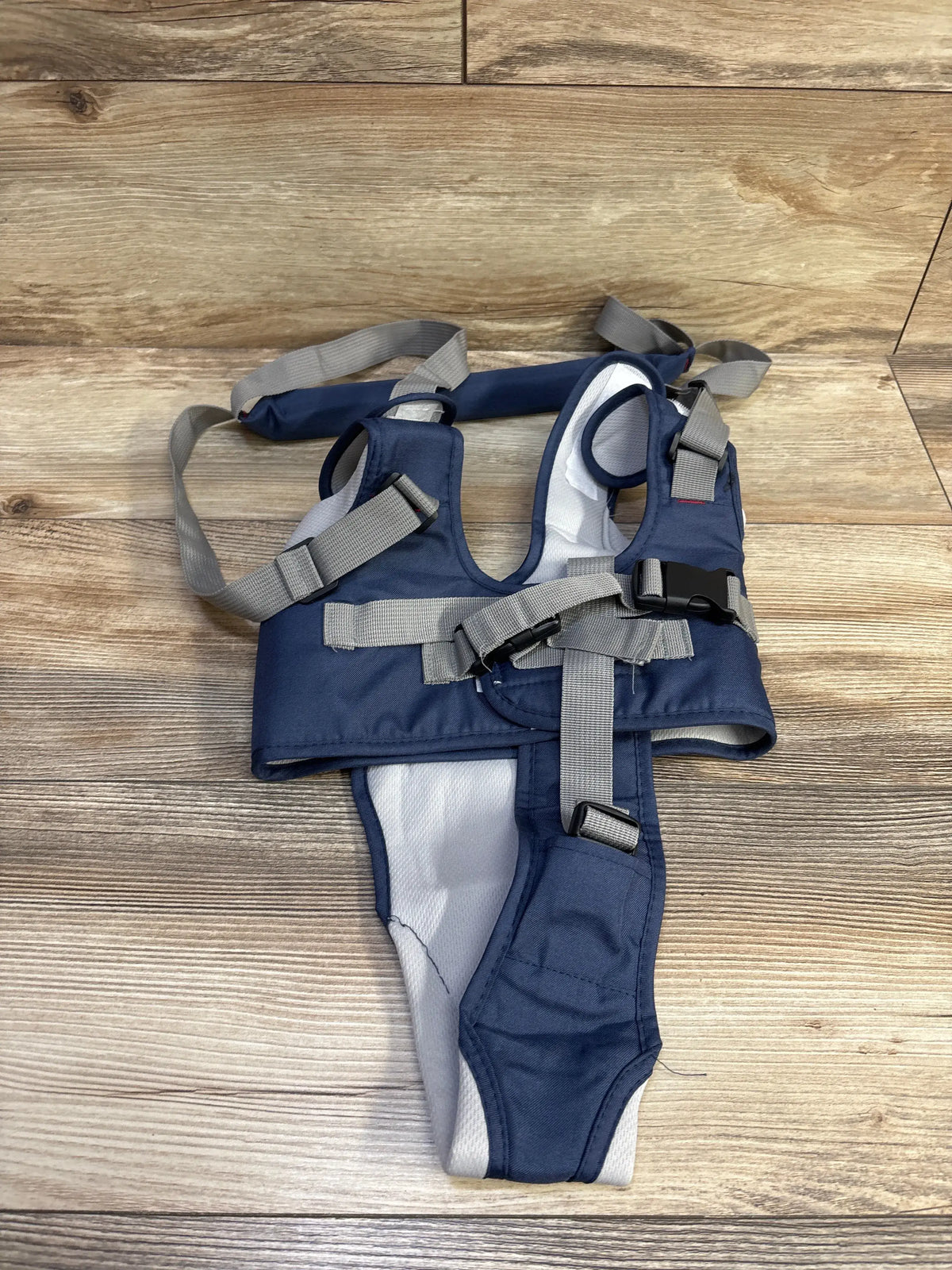 Top view of blue Han Han Rabbit baby walking harness showcasing gray straps and buckles with a wood-look floor background
