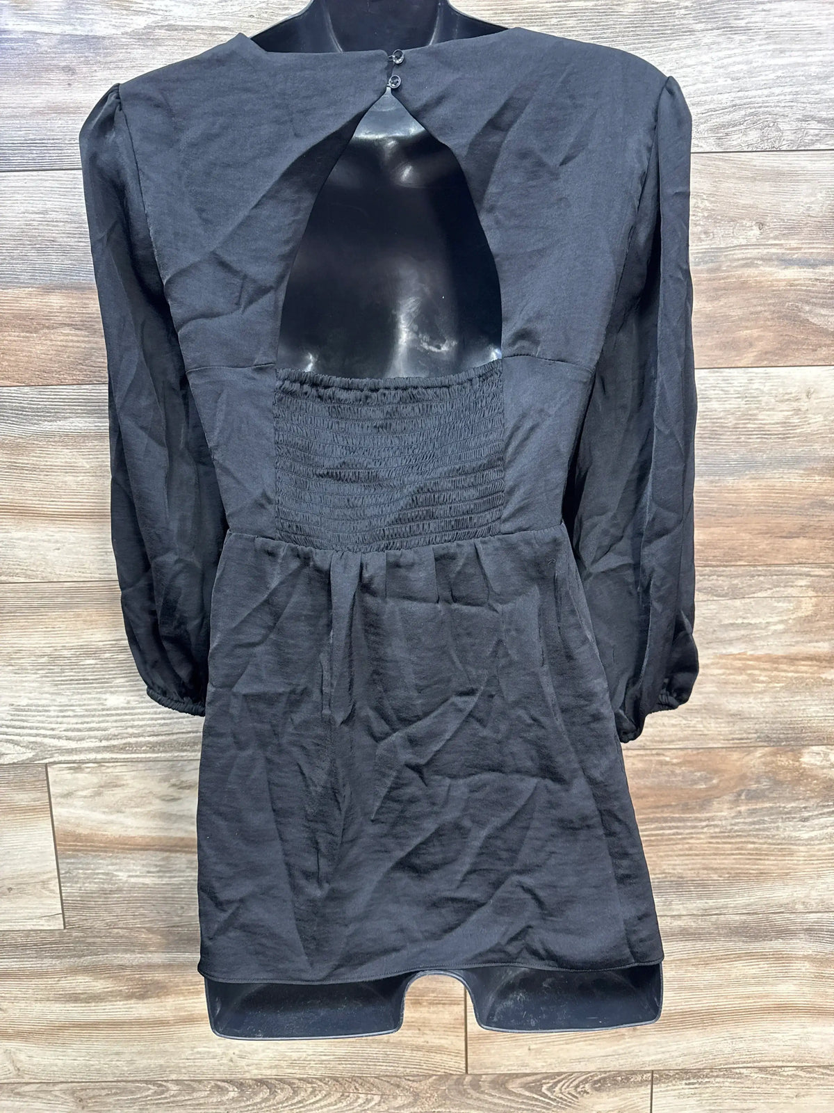 Front view of Isabel Maternity black long sleeve blouse size XL showcasing keyhole cutout and smocked waist on black mannequin with wood plank background