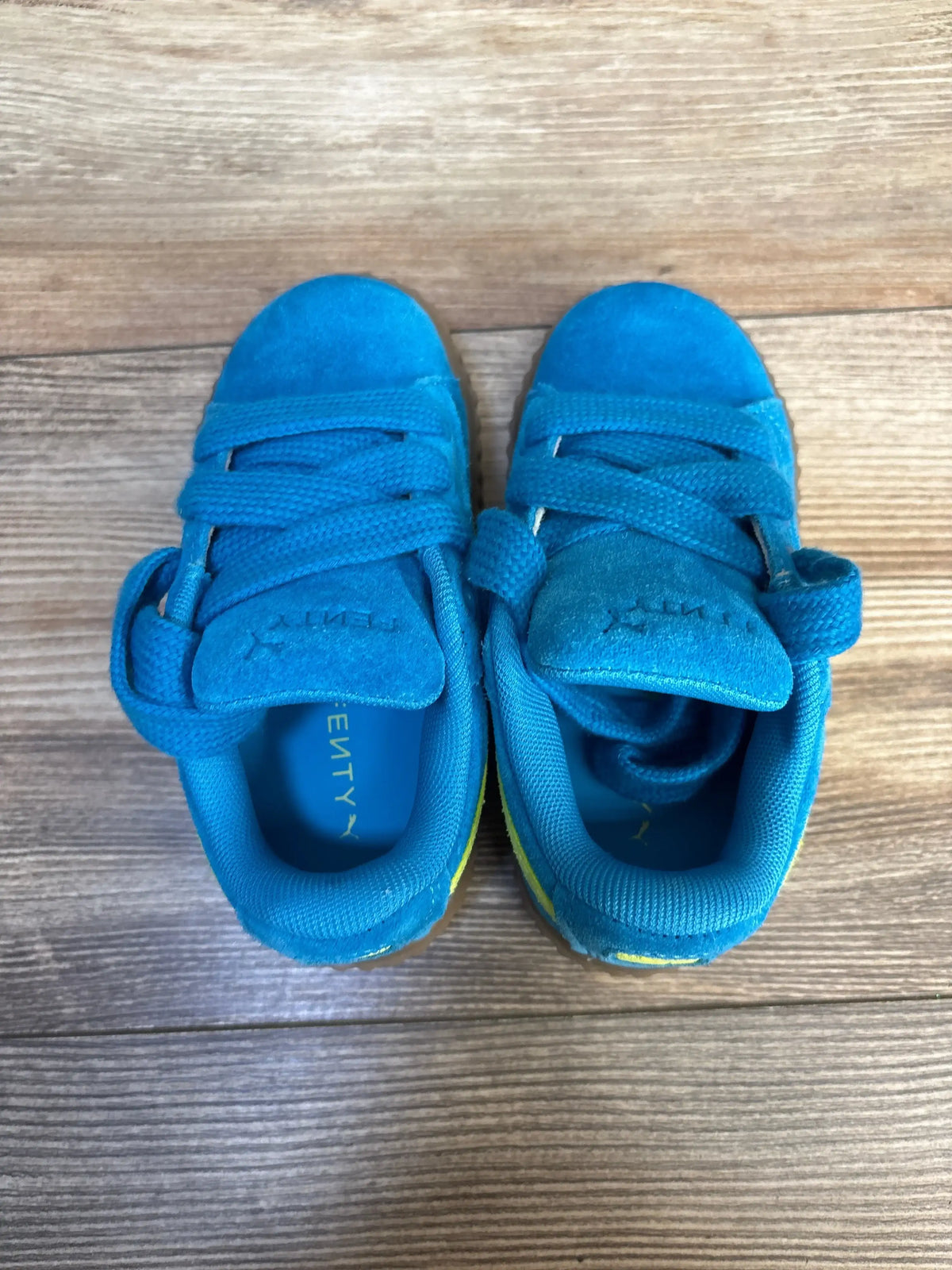 Top-down view of Puma x Fenty Creeper Phatty toddler sneakers in bright blue showing laces and velcro strap on wood floor