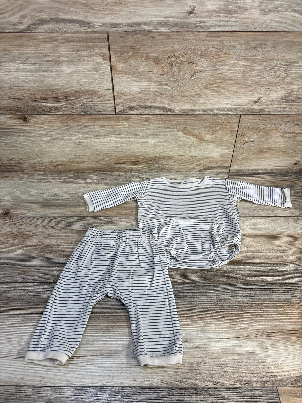 Flat lay of H&M organic two-piece striped long-sleeve bodysuit and pants set in cream tones on a wood surface