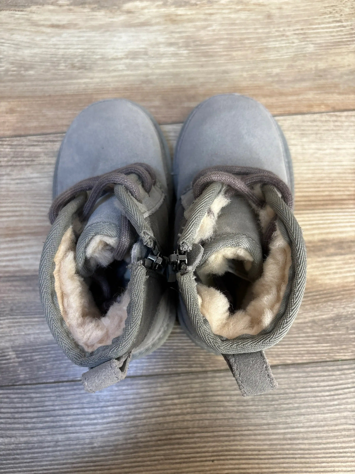 Top view of Ugg Neumel II toddler boots in grey, size 8C, showing plush faux-shearling lining and lace-up front on wood floor