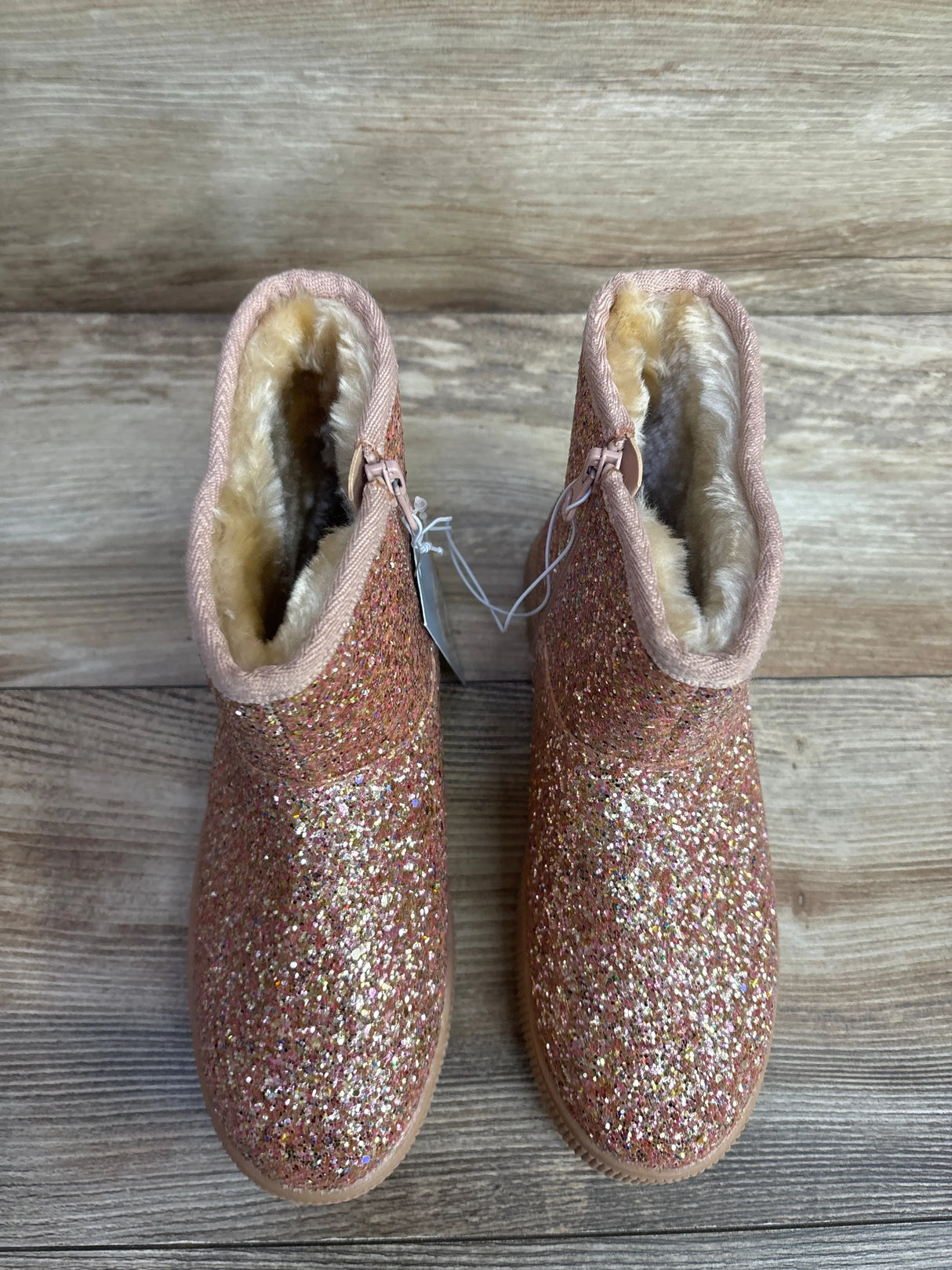 Sparkly pink glitter toddler boots with faux fur lining on wooden floor