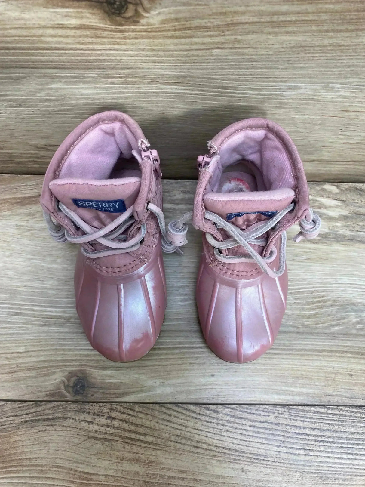Top down view of pink Sperry duck boots, toddler size 6C, showing rubber toe and lace up closure on wooden floor