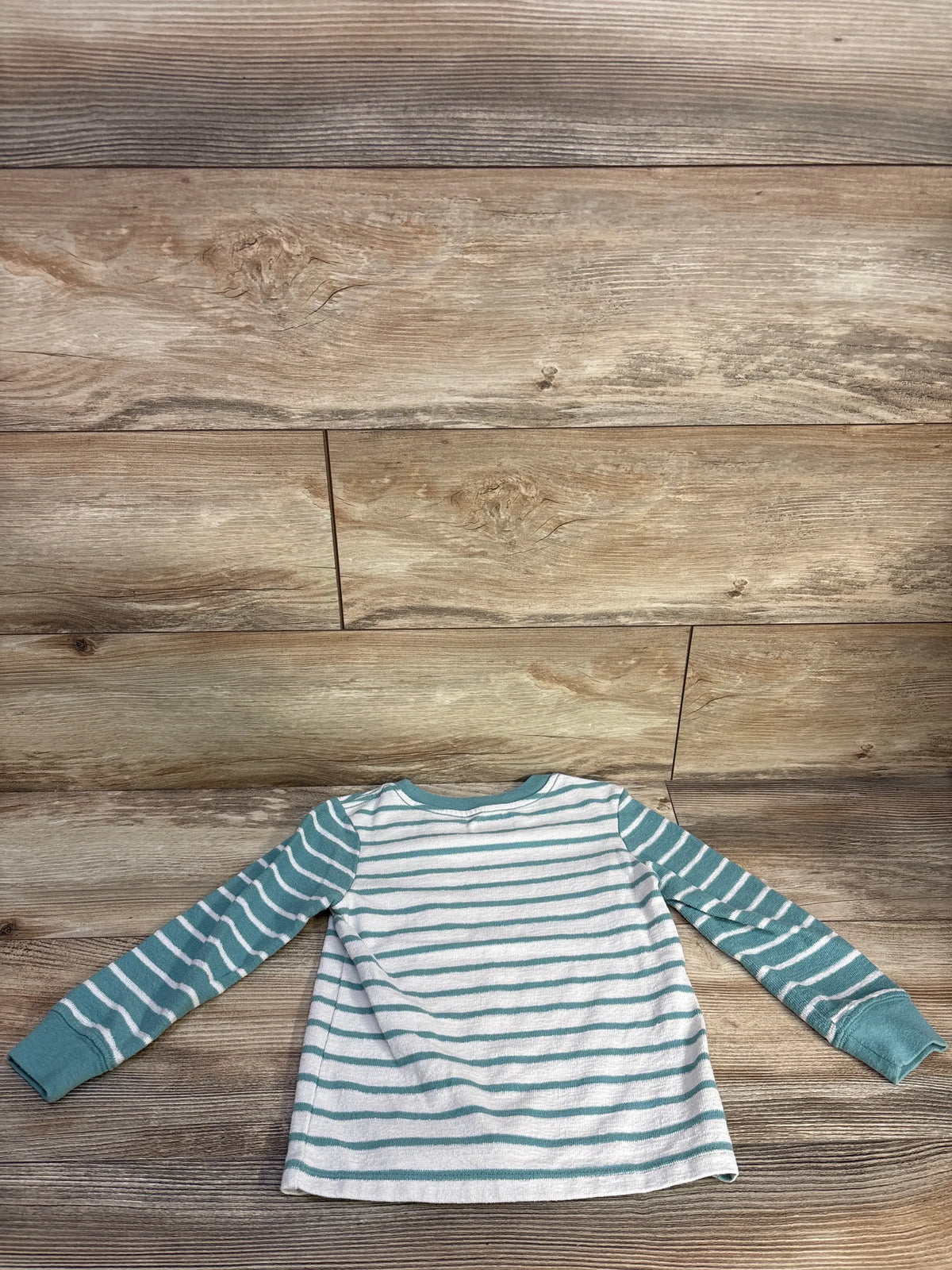 Front view of Cat & Jack teal striped pocket shirt, size 4T, with long sleeves and chest pocket on wood background