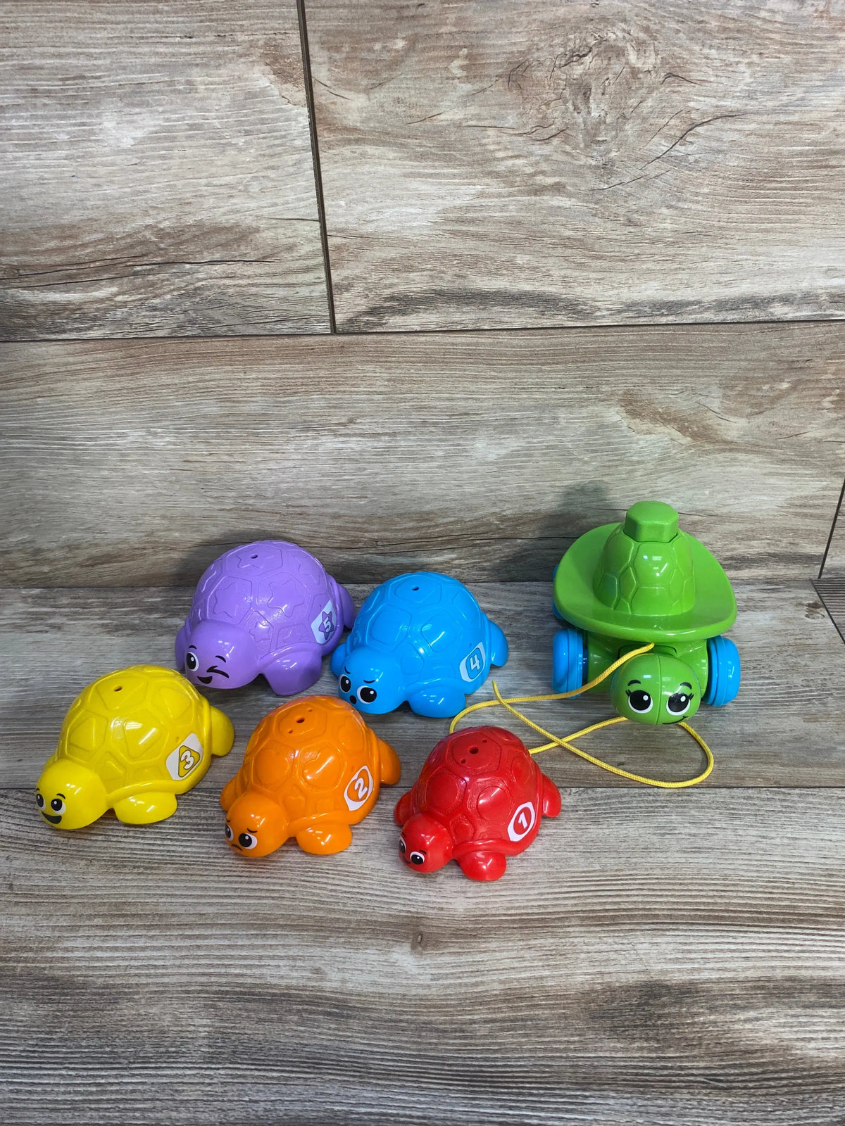 Front view of LeapFrog Nest & Count toy with six numbered nesting turtles and a green pull along turtle on wood background