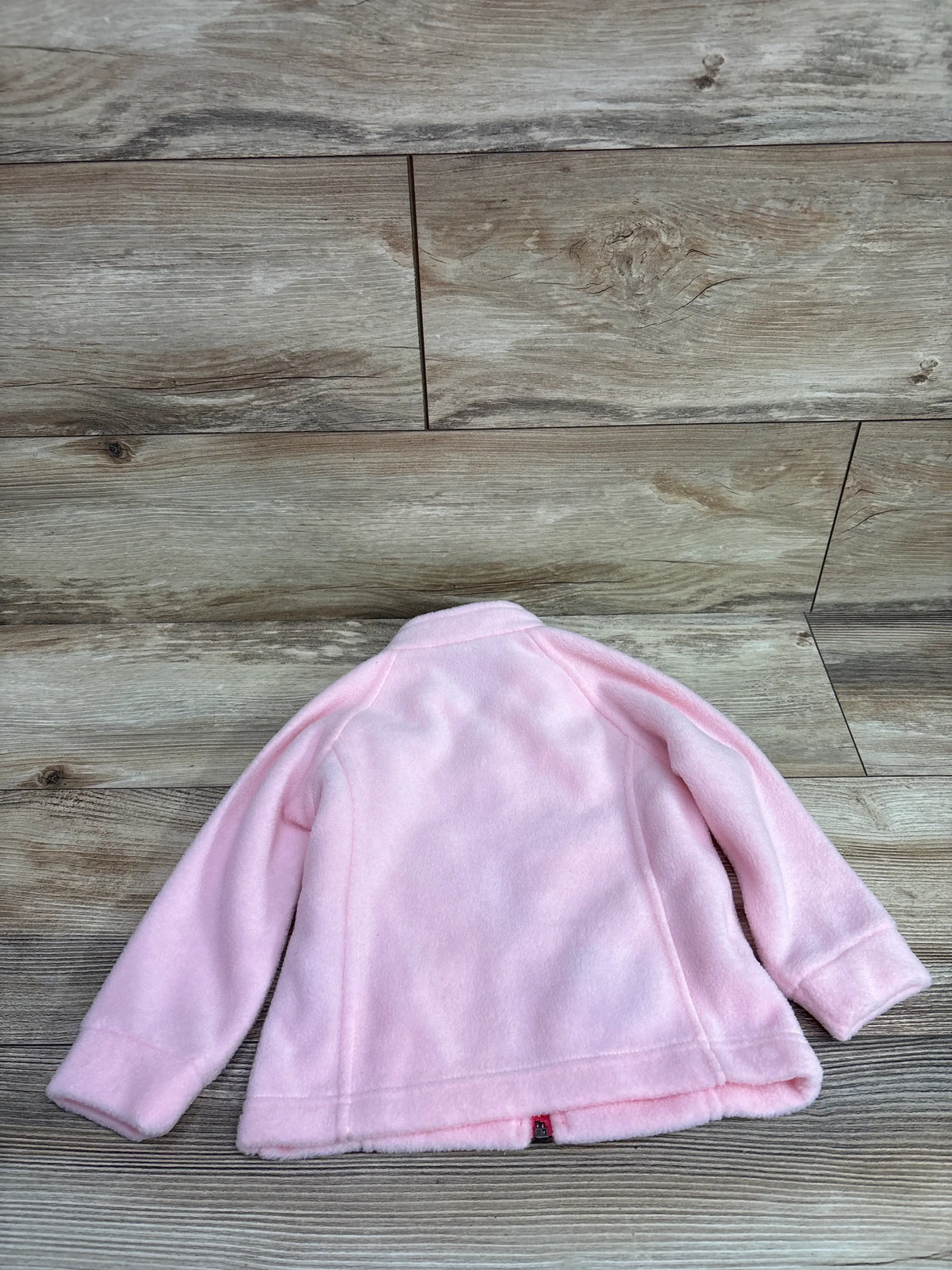 Columbia fleece full zip jacket in pink for size 2T, laid flat on a wood grain surface.