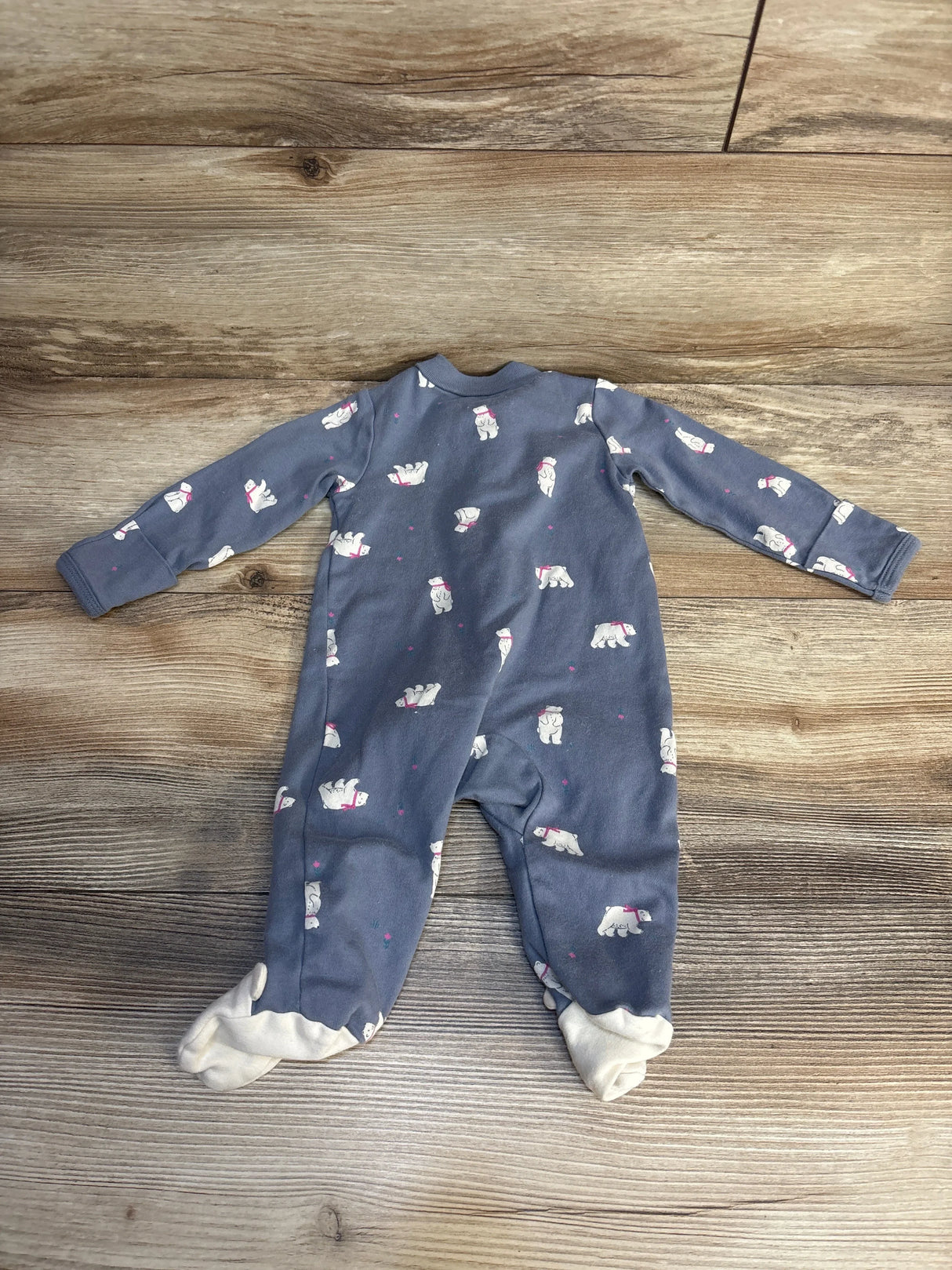 Blue footed baby sleeper with polar bear print, laid flat on wood floor
