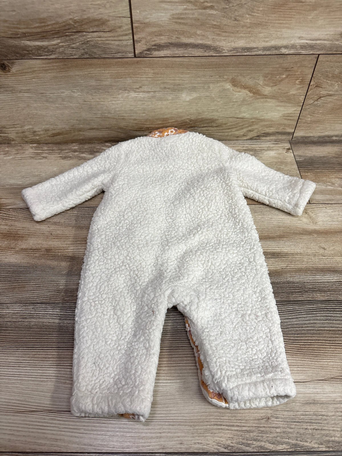 Top view of Nicole Miller white sherpa coverall showcasing long sleeves and full-length legs on a wood-look floor