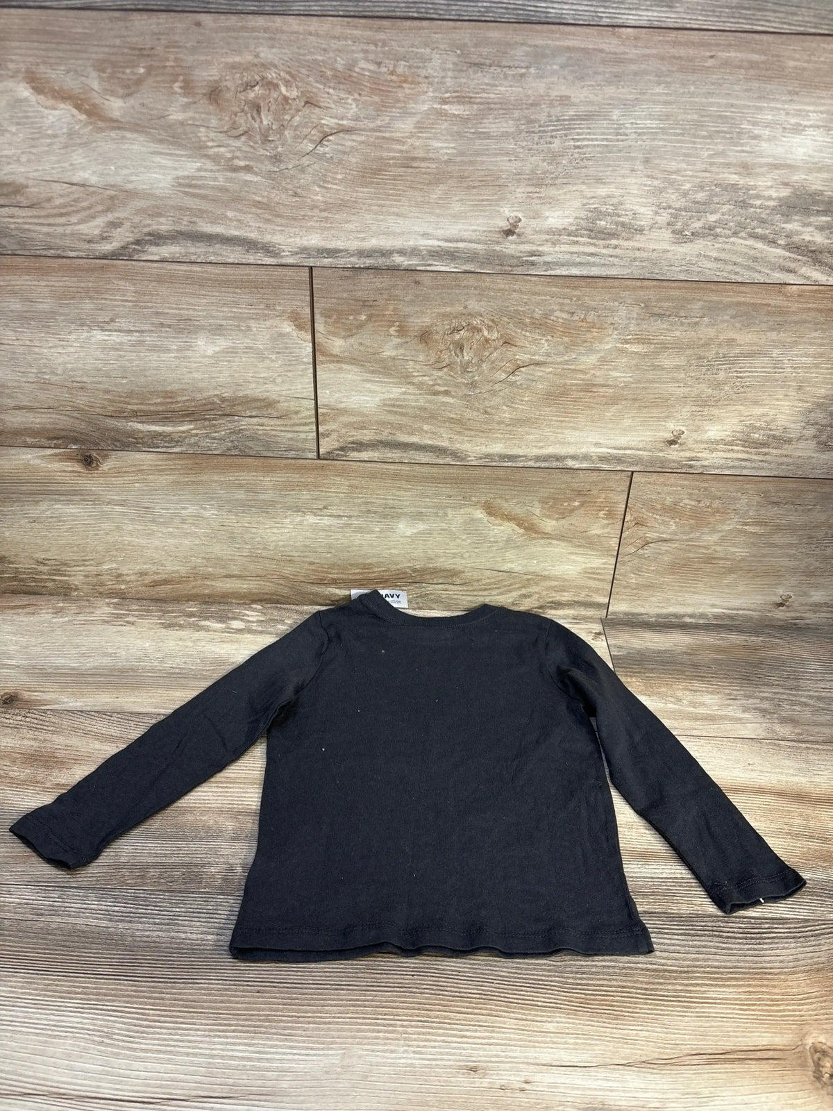 Back view of Old Navy Dream Builder long-sleeve shirt size 4T showing long sleeves and slight scalloped hem on wood background
