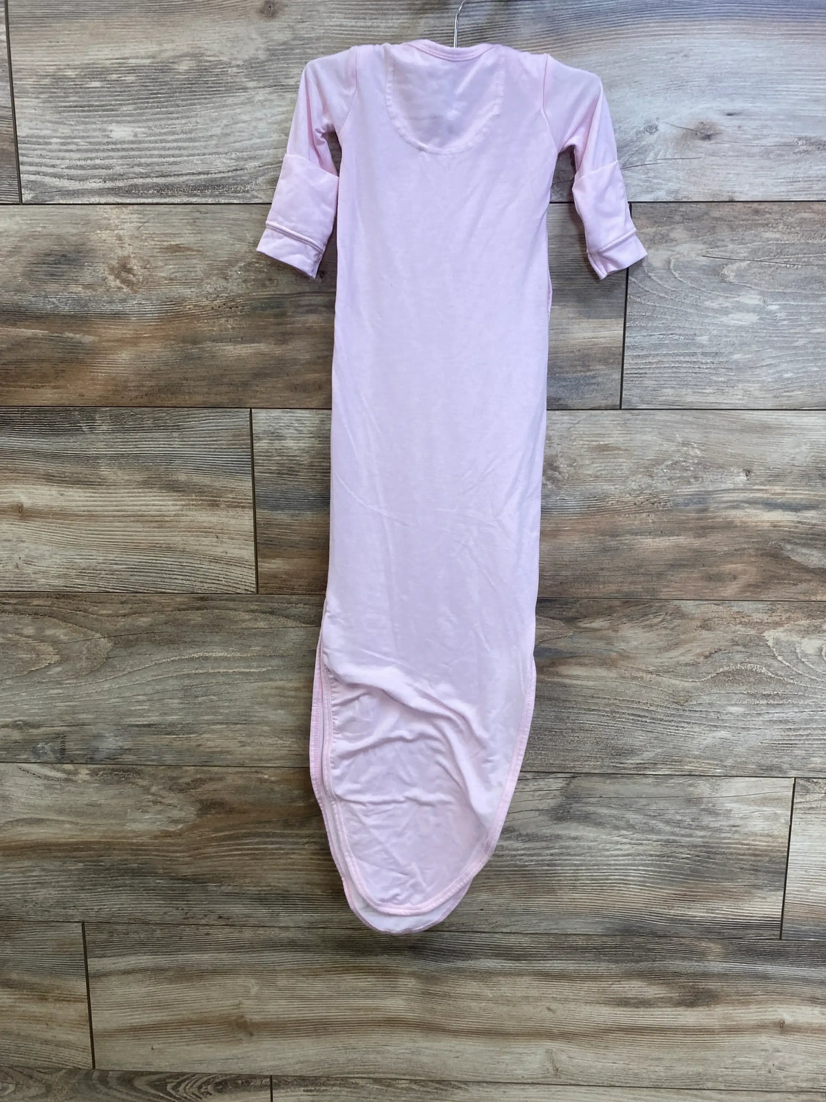 Front view of pink Copper Pearl knotted newborn gown showing long cuffed sleeves and knotted bottom on wood plank background