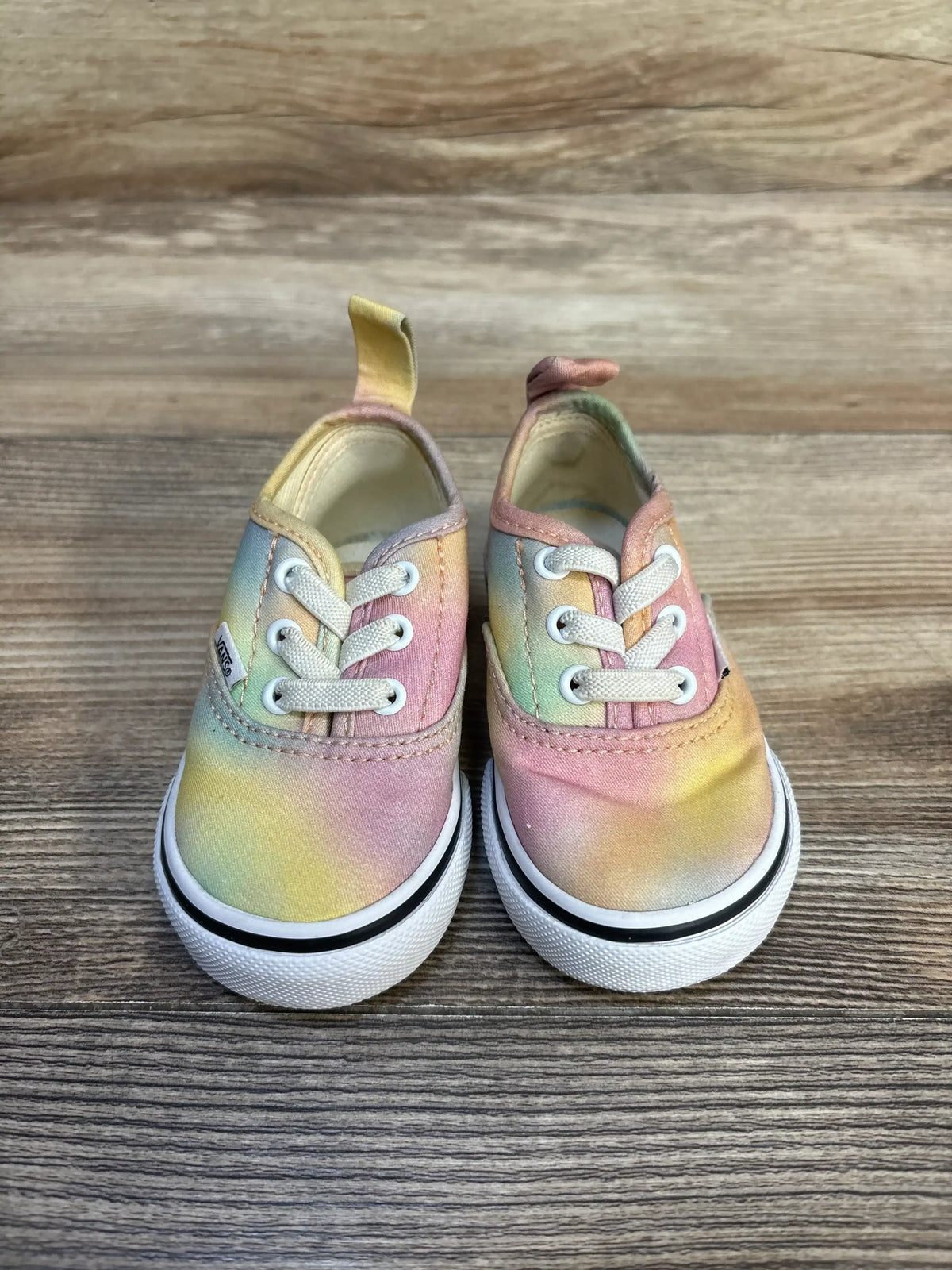 Pastel tie-dye toddler sneakers with white laces on wood background