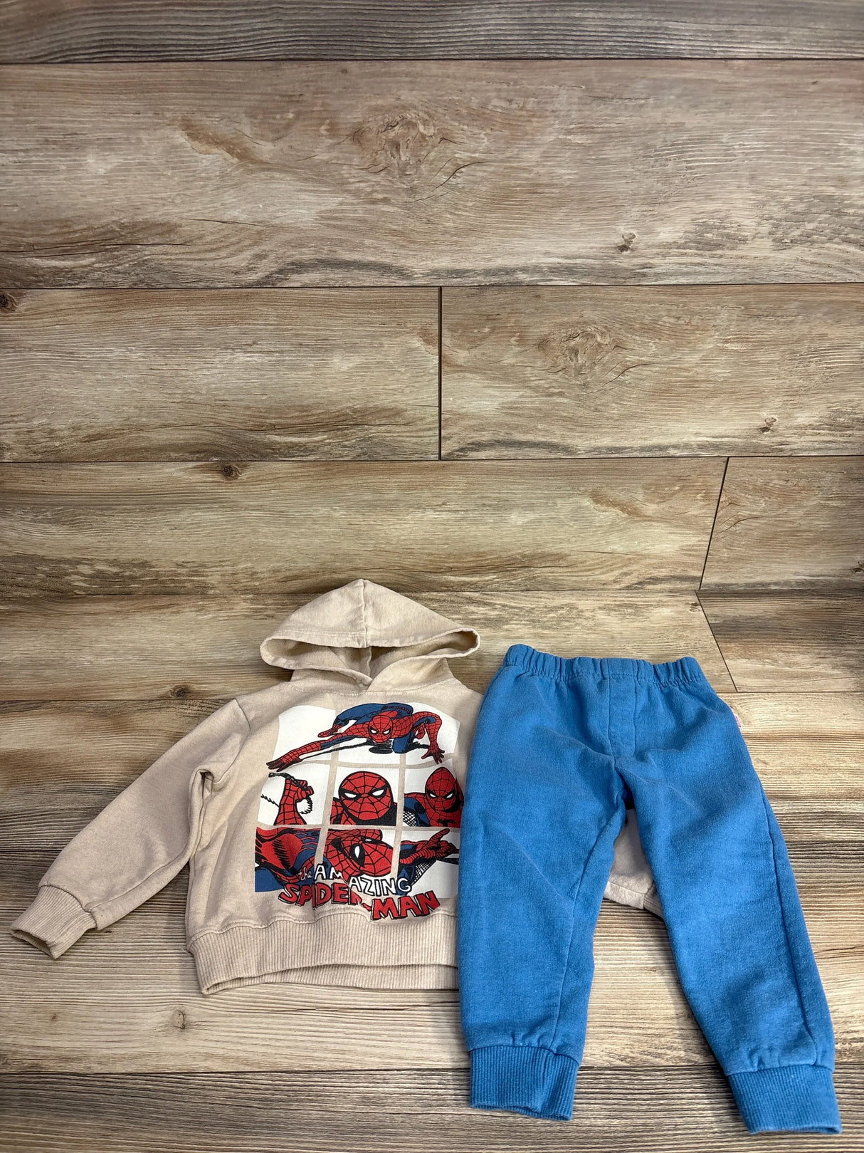 Kids Spider-Man hoodie and blue jogger pants set on wood background