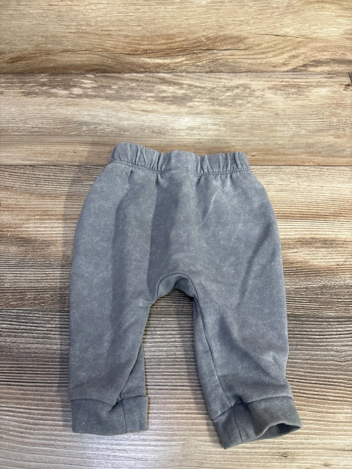 Front flat lay of grey Cat and Jack newborn pull-on joggers showing elastic waistband and cuffed ankles on wood background