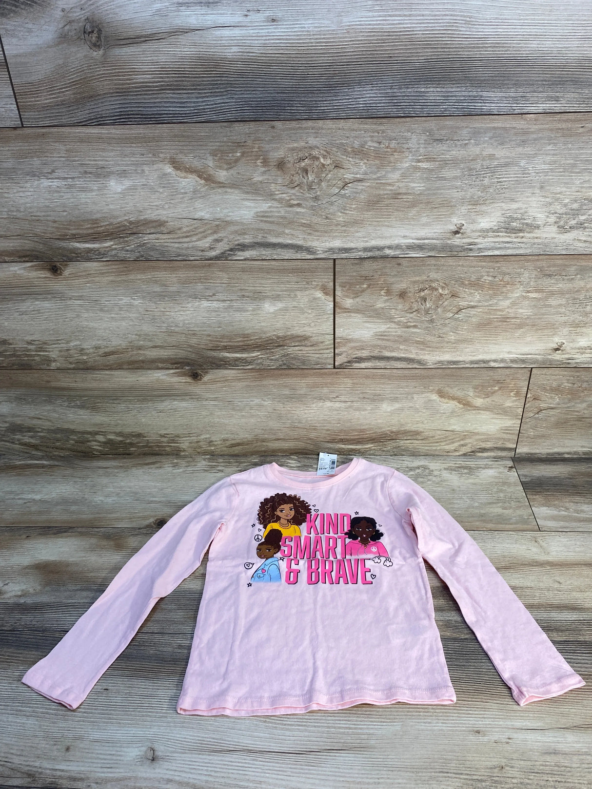Pink long sleeve girls shirt with 'Kind Smart & Brave' graphic and cartoon characters, laid flat