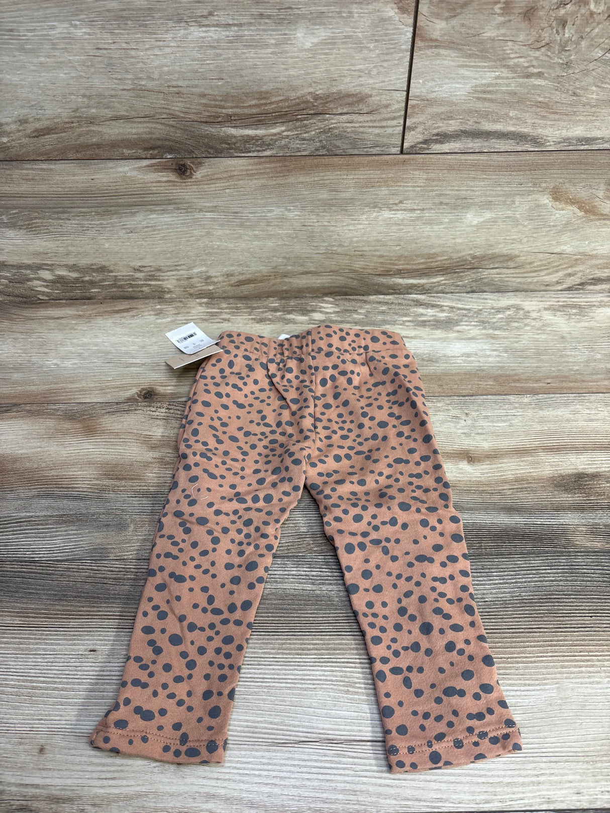 Brown toddler leggings with black polka dot pattern on a wooden floor