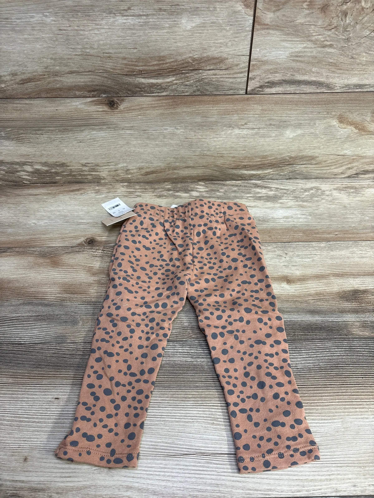 Brown toddler leggings with black polka dot pattern on a wooden floor