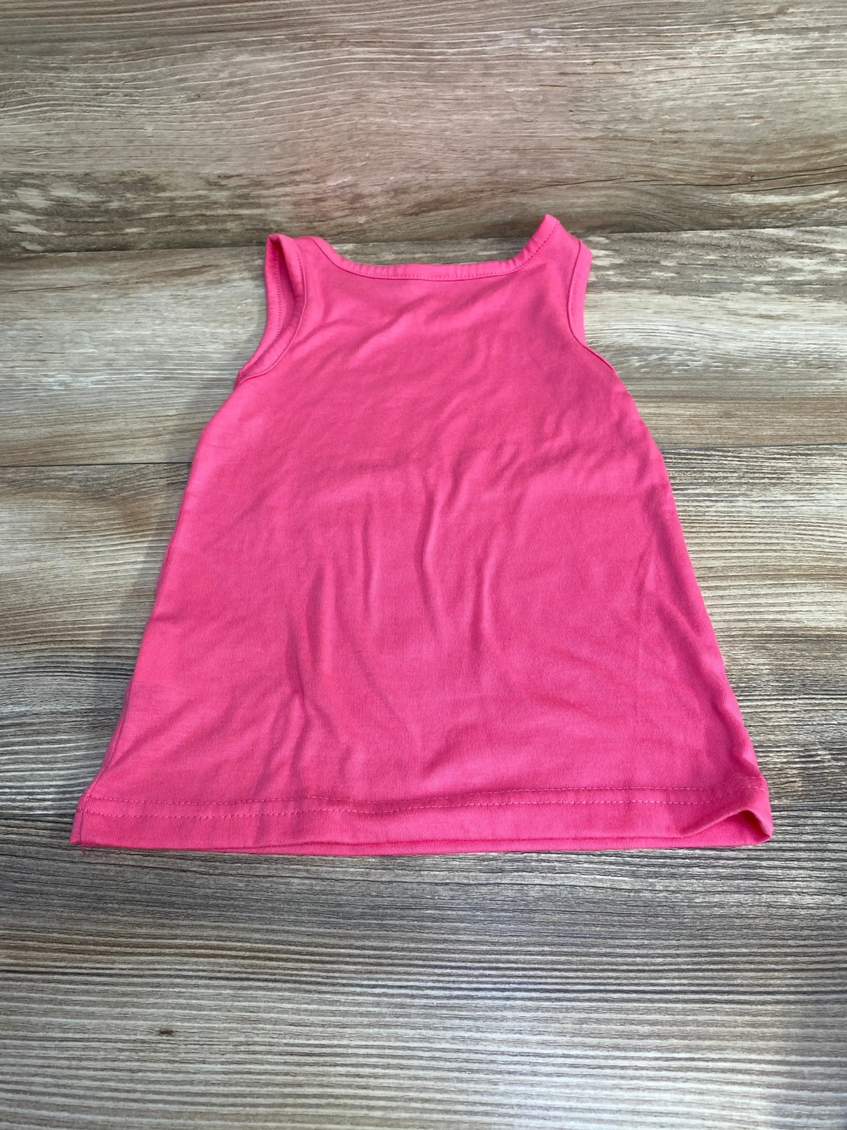 Flat-lay of baby pink sleeveless tank dress 6 to 9 months showing A-line shape and solid color on wood background
