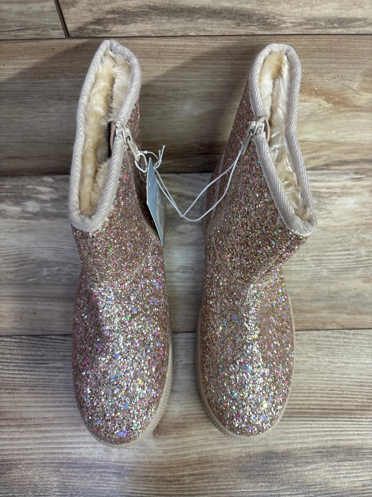 Glittery pink toddler boots with faux fur lining on wooden floor