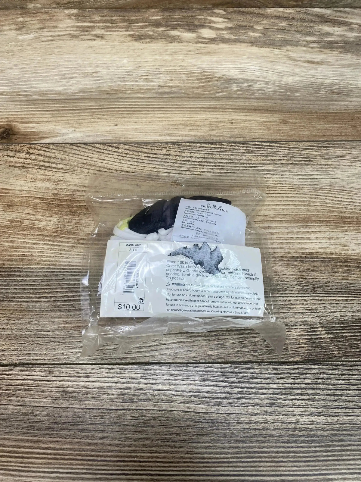 Top-down view of 3-pack kids reusable masks in grey and green showing adjustable ear loops in clear plastic packaging on wood background