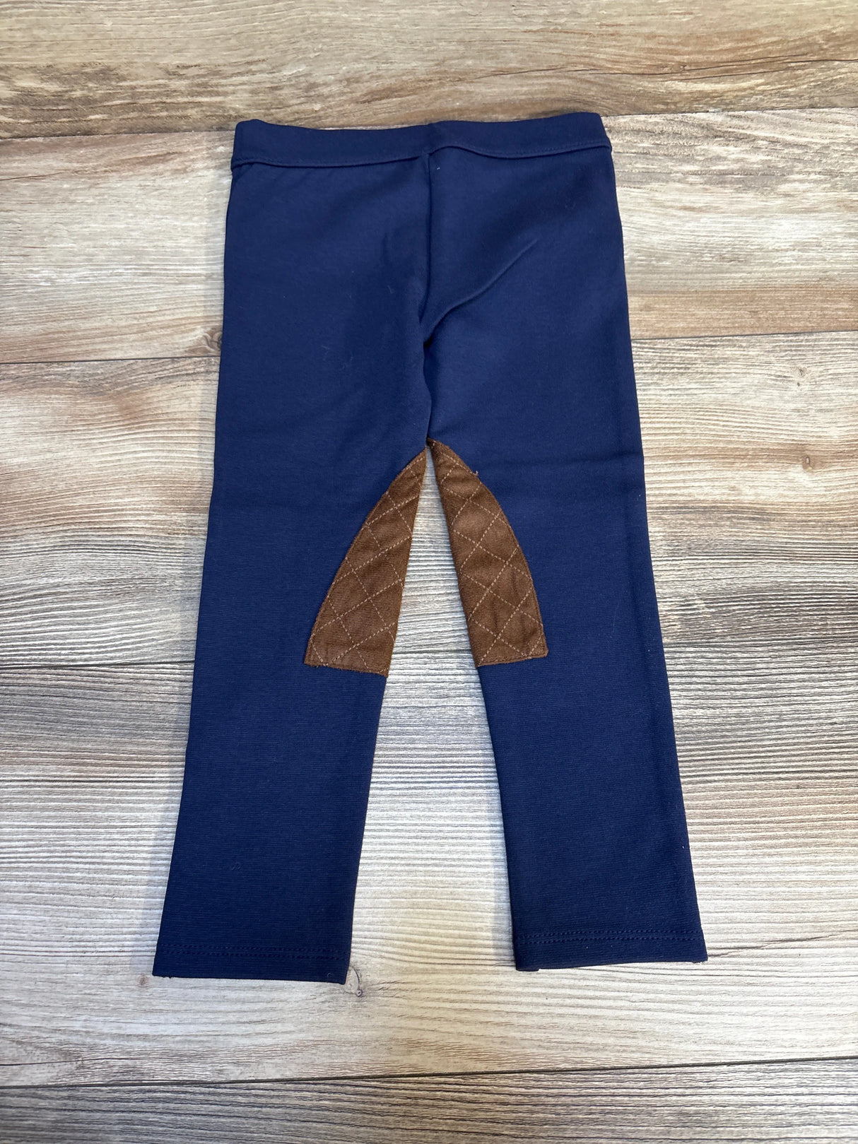 Navy blue kids leggings with brown quilted knee patches on wood background