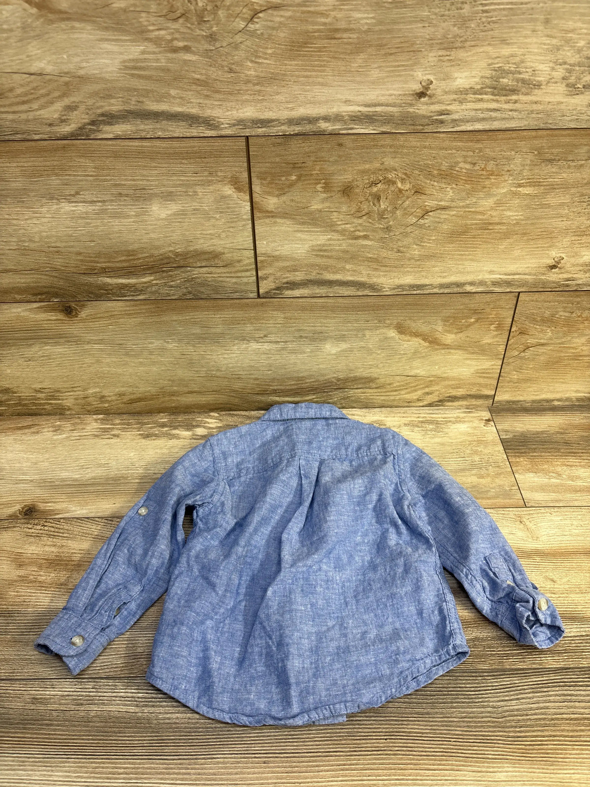 Back view of a blue Gymboree button up shirt for toddlers size 2T on a wood background.