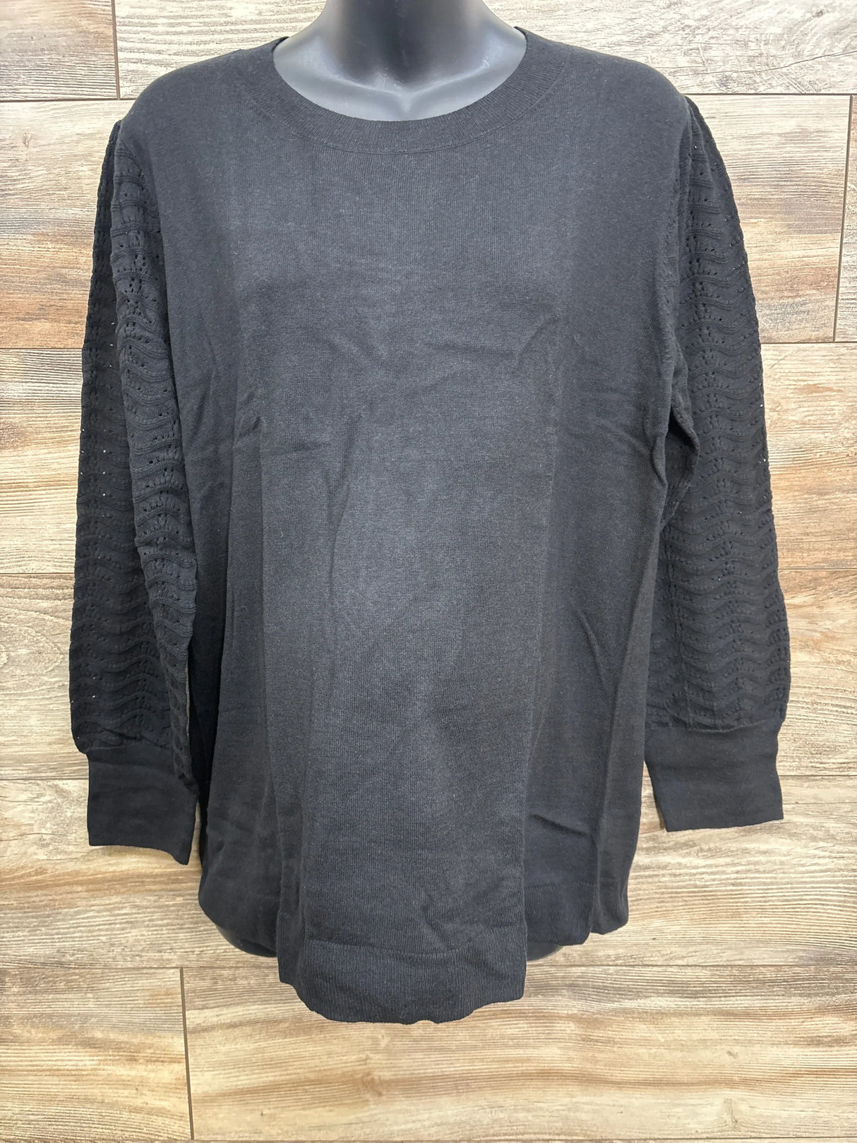 Black long-sleeve knit sweater with lace patterned sleeves on mannequin against wooden background