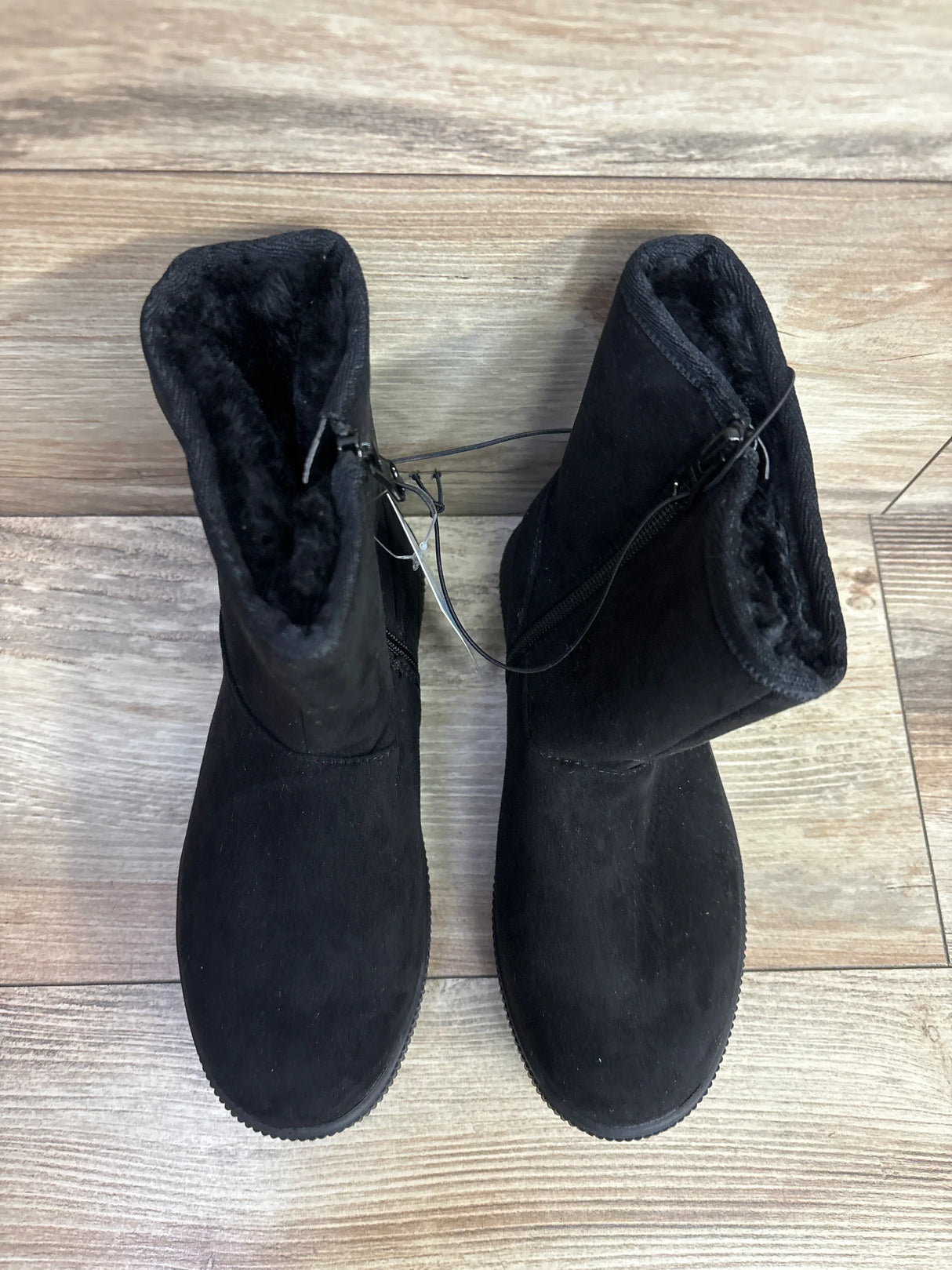 Pair of black suede kids winter boots with faux fur lining on wood floor