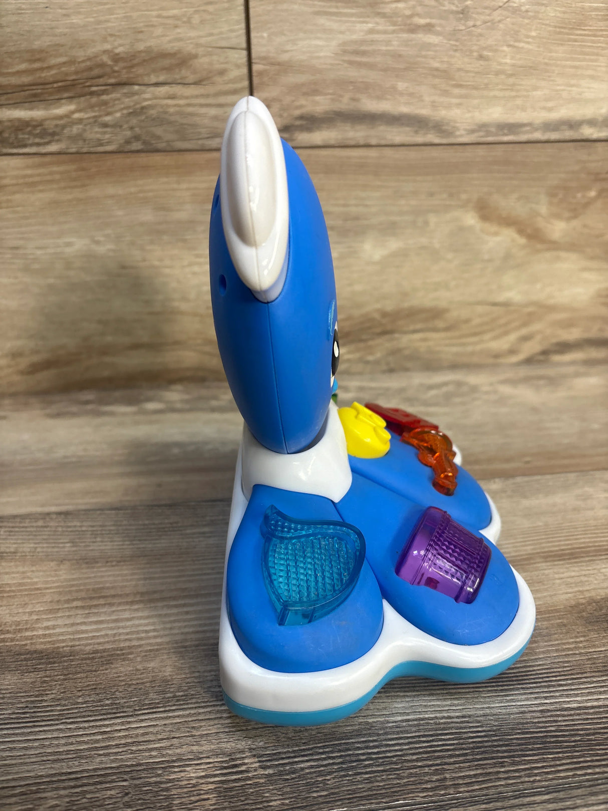 Blue plastic interactive baby toy with textured buttons on wood surface