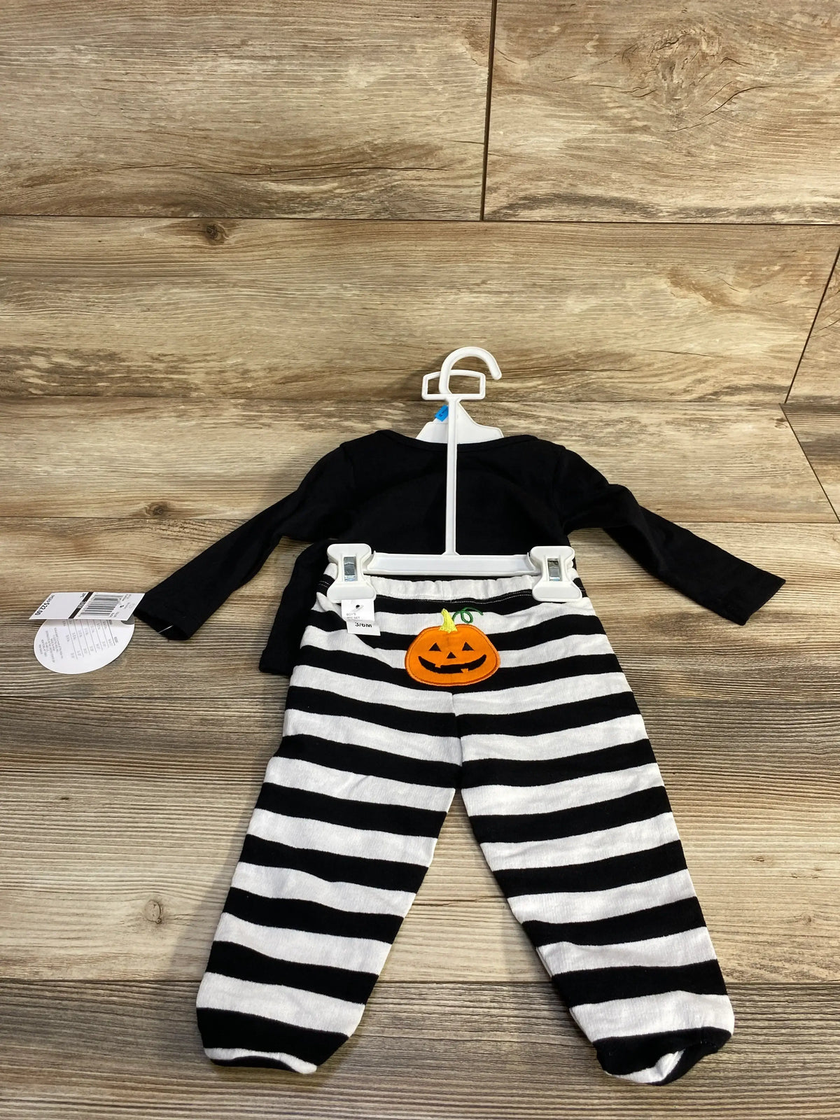 Front view of 2-piece Halloween outfit showcasing a black bodysuit and black-and-white striped pants with jack-o-lantern