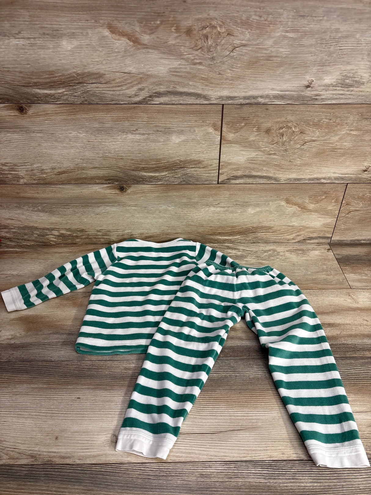 Green and white striped toddler pajama set on wood floor, long sleeve shirt and pants