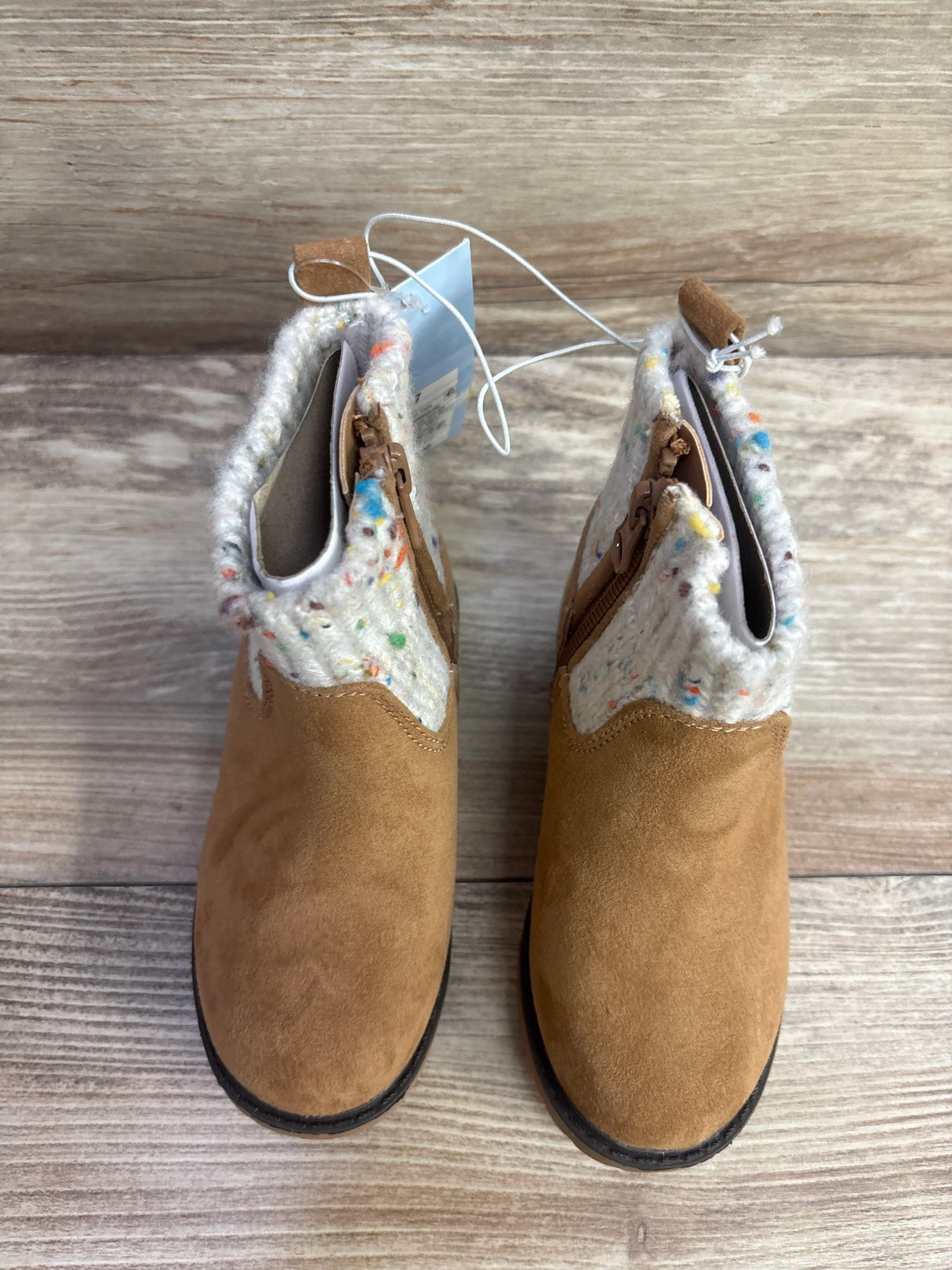 Pair of tan suede toddler boots with cozy speckled knit cuffs and side zippers on wood floor