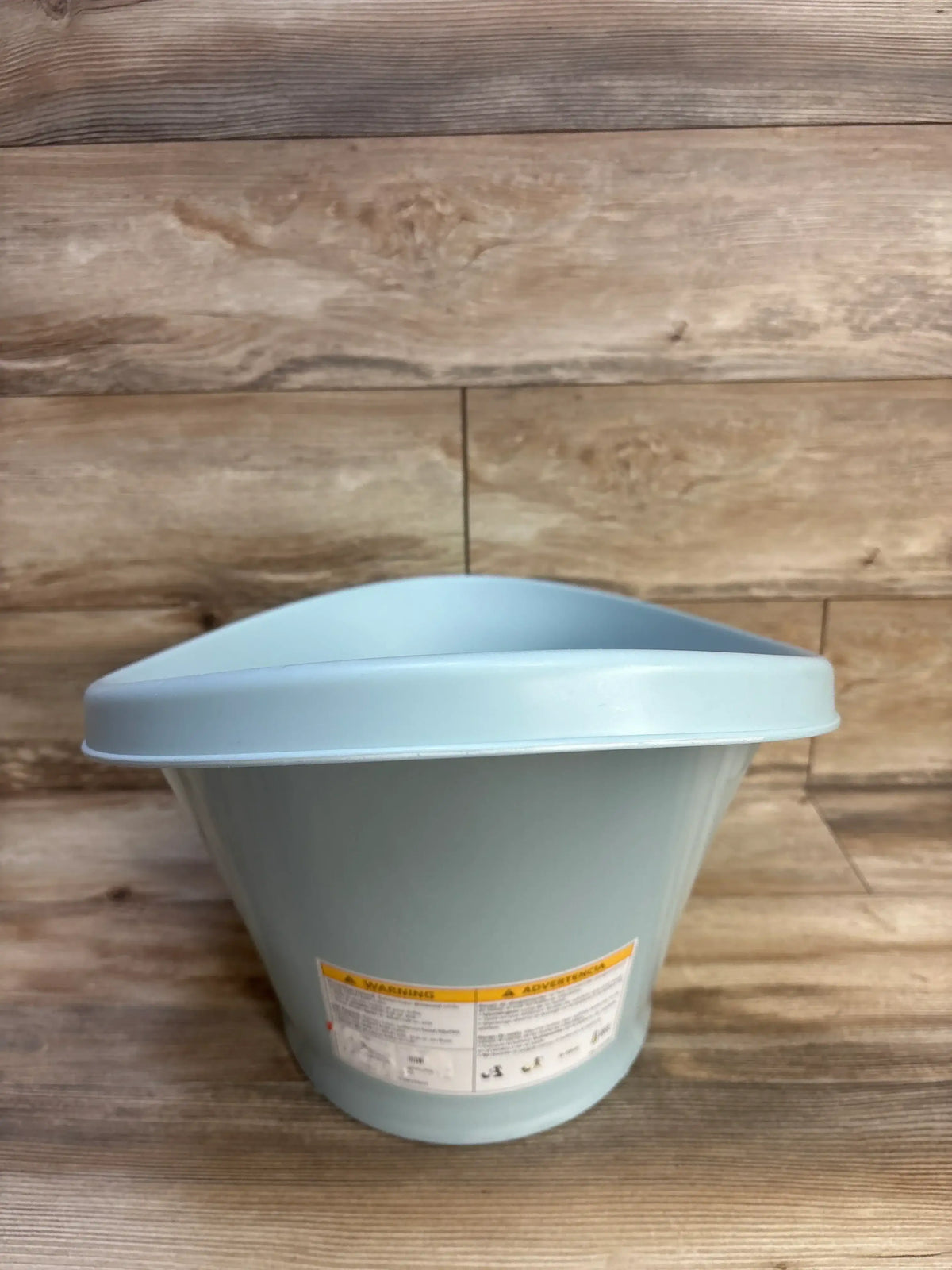 Front view of BEABA by Shnuggle baby bath tub, light blue, showing curved backrest and warning label on wood background