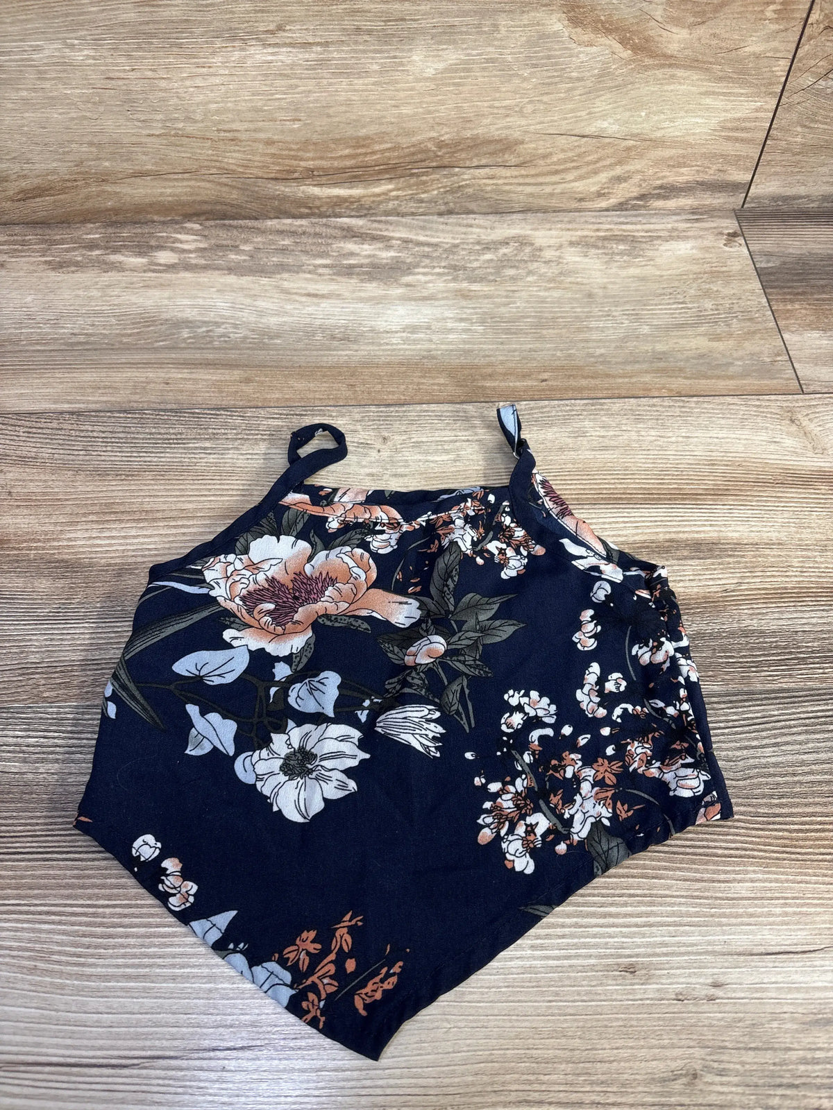 Top view of Shein cropped tank top in navy showcasing floral print and thin straps on a wood floor