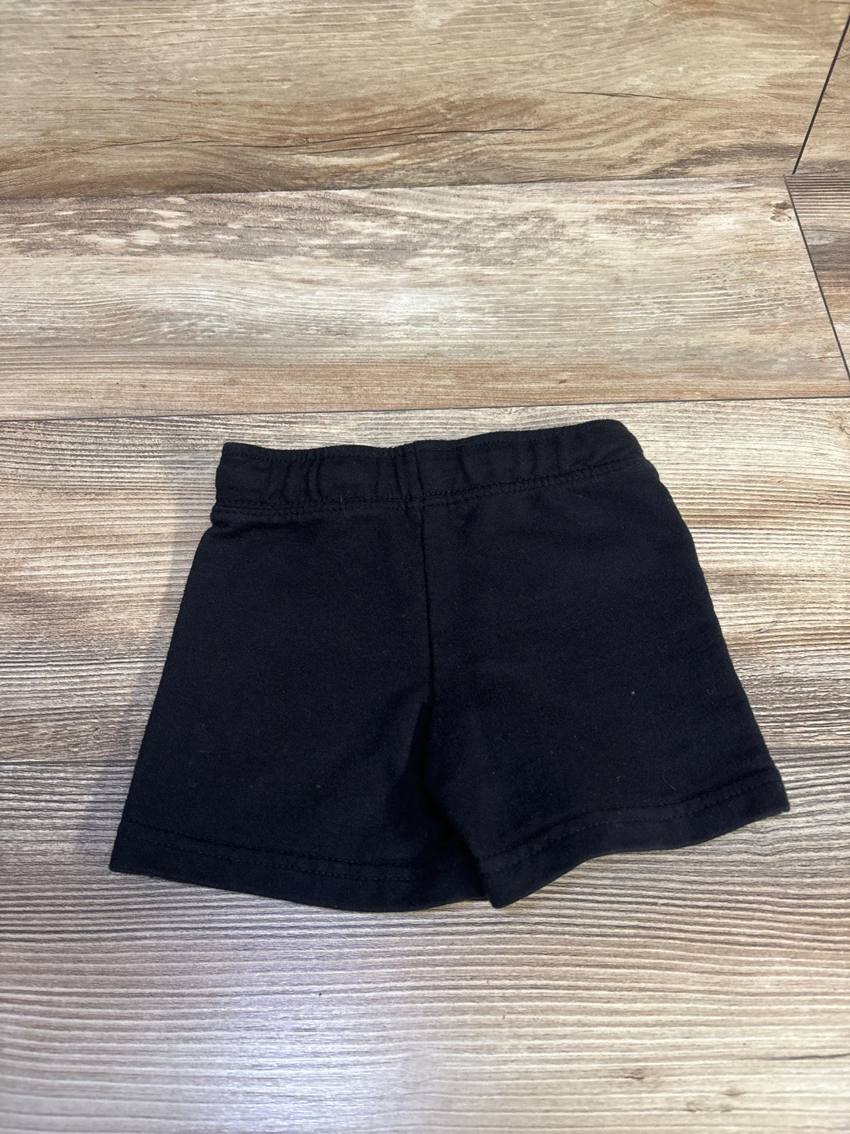 Cat & Jack drawstring black shorts for babies size 12m on a wooden surface